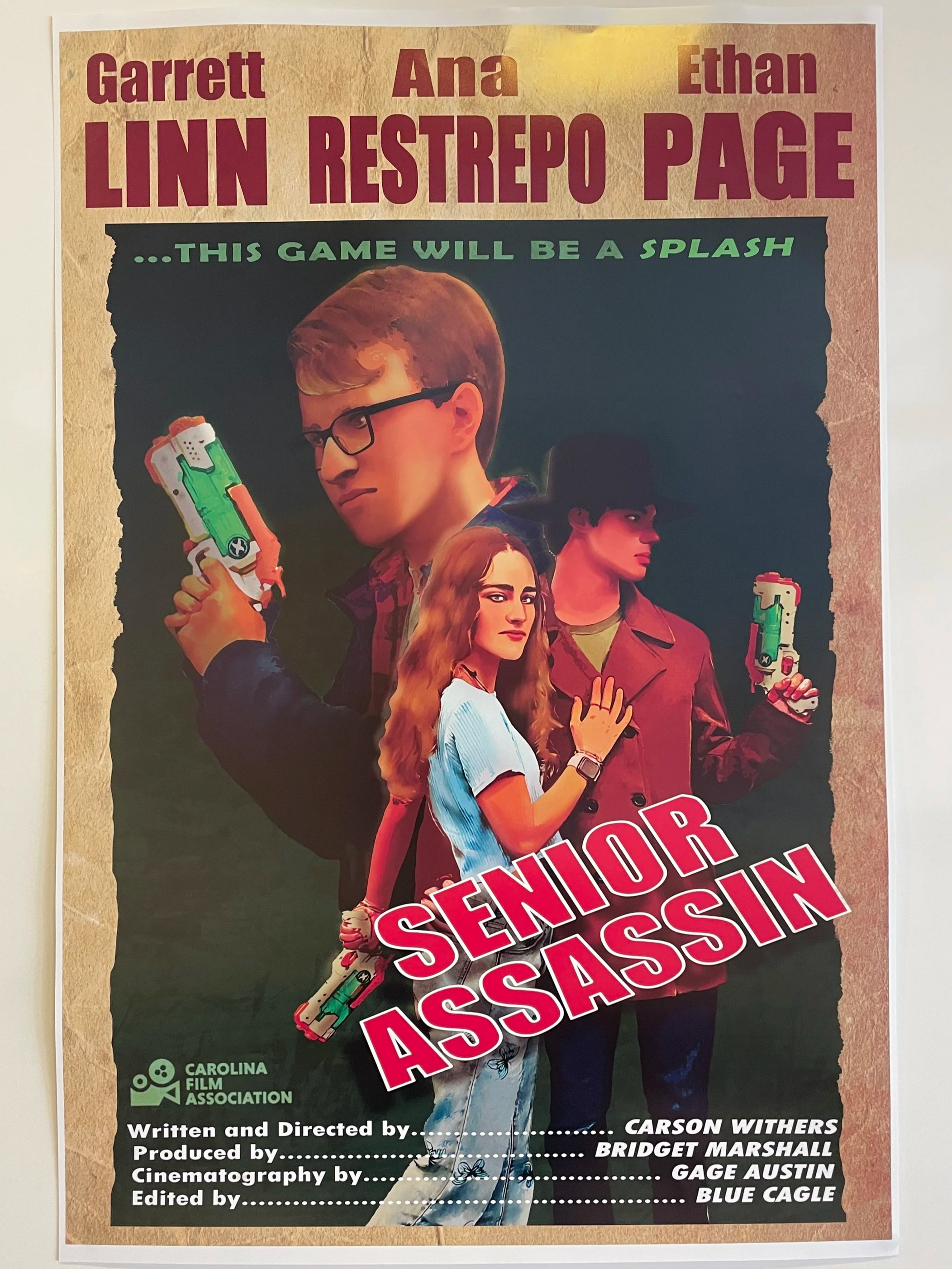 Poster for the movie 'Senior Assassin' featuring three young characters holding water guns, with the movie title prominently in red and white text. The movie stars Ethan Page, Ana Restrepo, and Garrett Linn