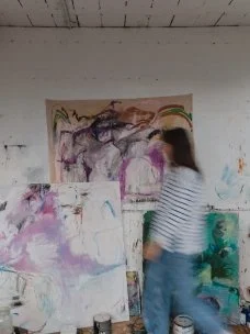 Person working on abstract paintings in an art studio.