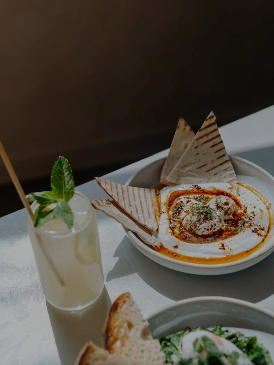 A bowl of Indian butter chicken with naan bread, a lemon soda with mint, and a slice of bread.