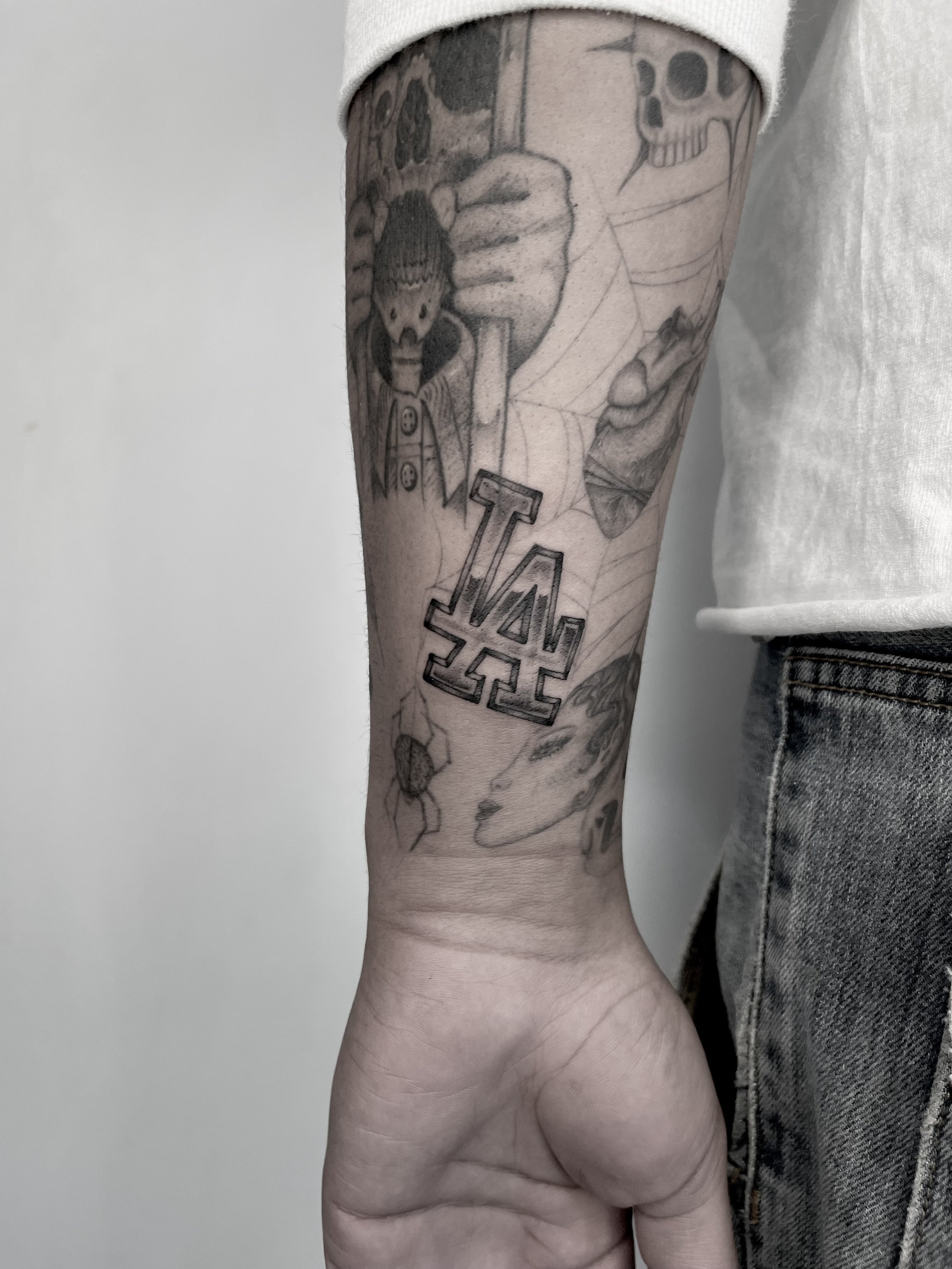Tattoo on person's arm featuring a snake, a skull, a spider web, and text with the letters 'V' and 'A'.