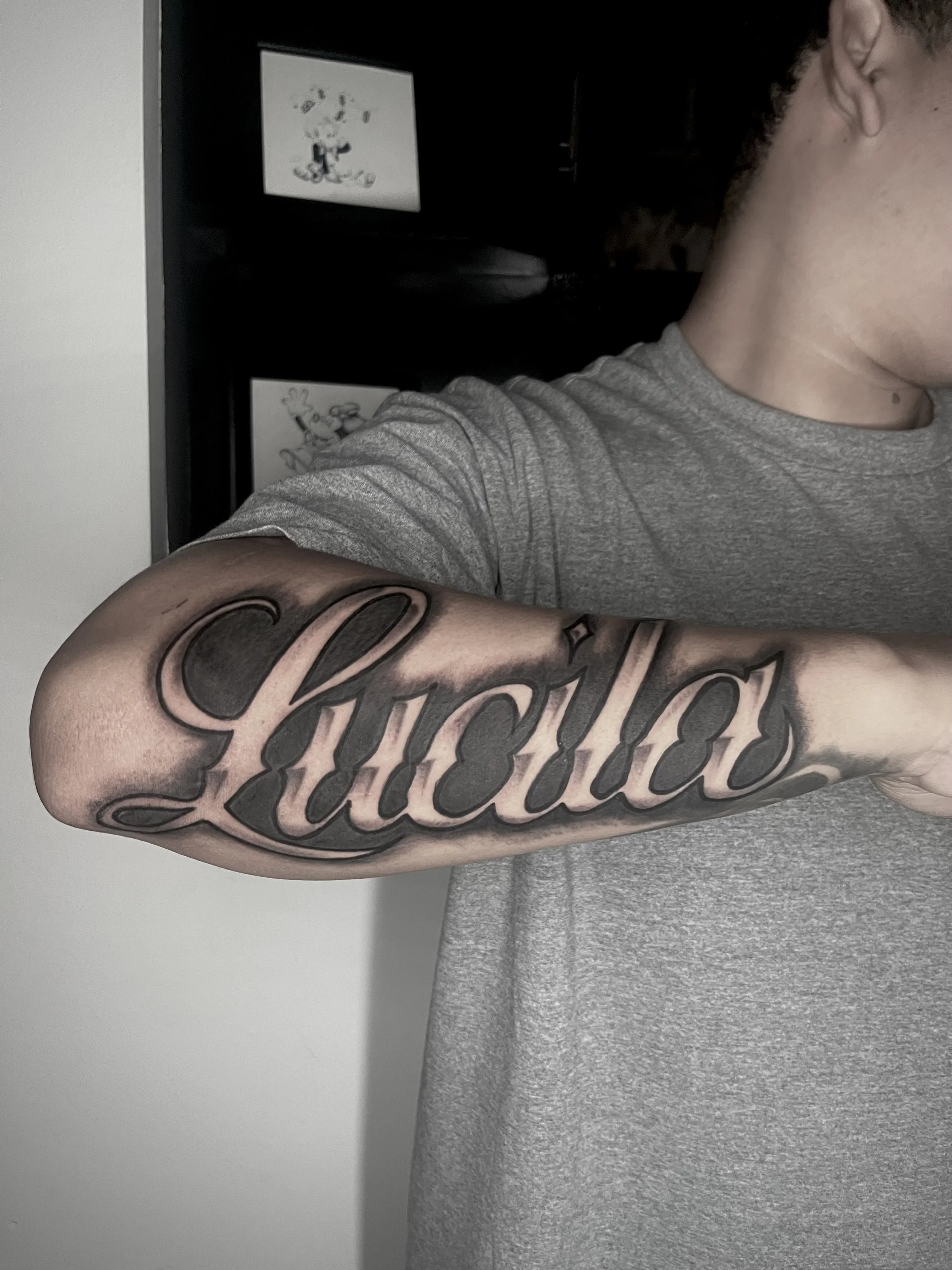 A person with a tattoo on their arm, showing the word 'Courage' in bold, black cursive letters.