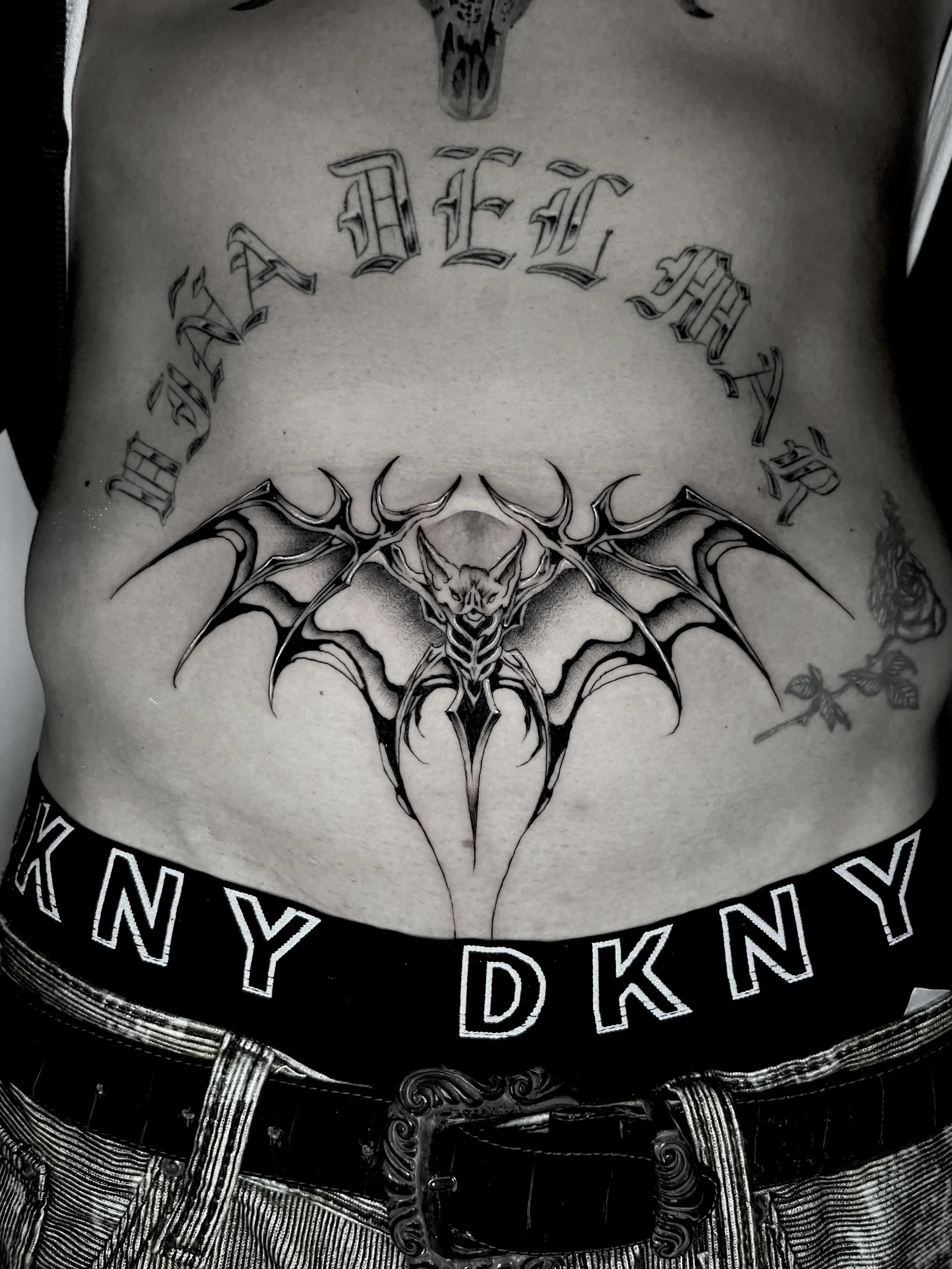 A person's chest tattoo featuring the words "FADED" in gothic lettering and a detailed bat-like creature with wings, surrounded by a circle of letters.