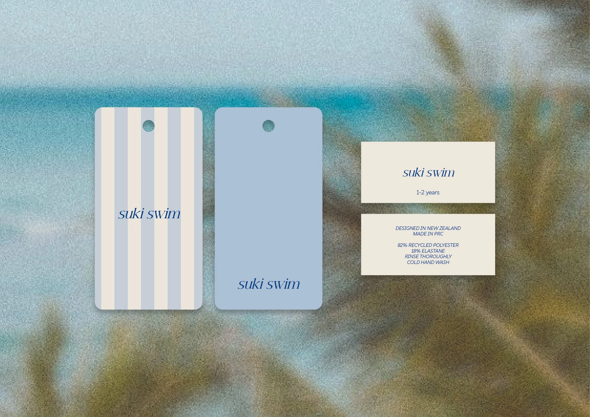 Various tags and tags with product information, including brand name Suki Swim, designed in New Zealand, made in PRC, and details about material and washing instructions. The background is blurred with colors of blue, brown, and white.