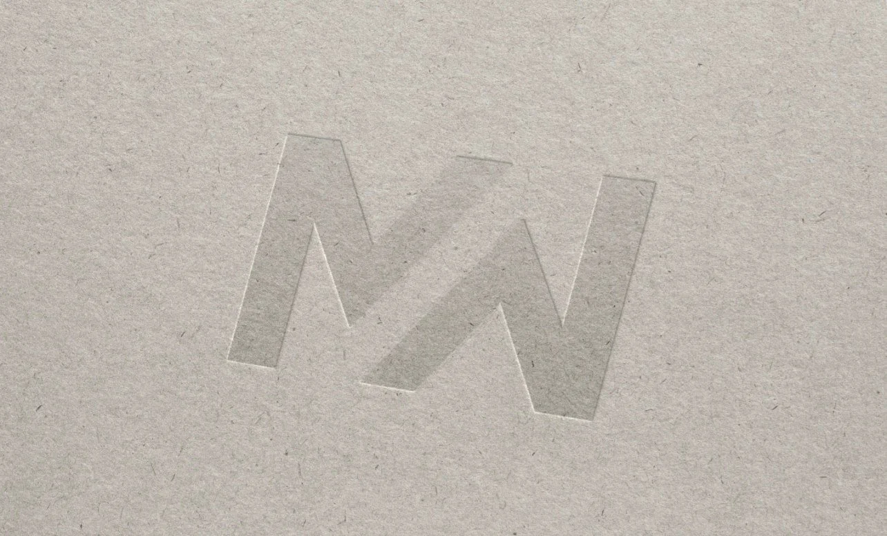 Embossed letter W on textured paper surface.