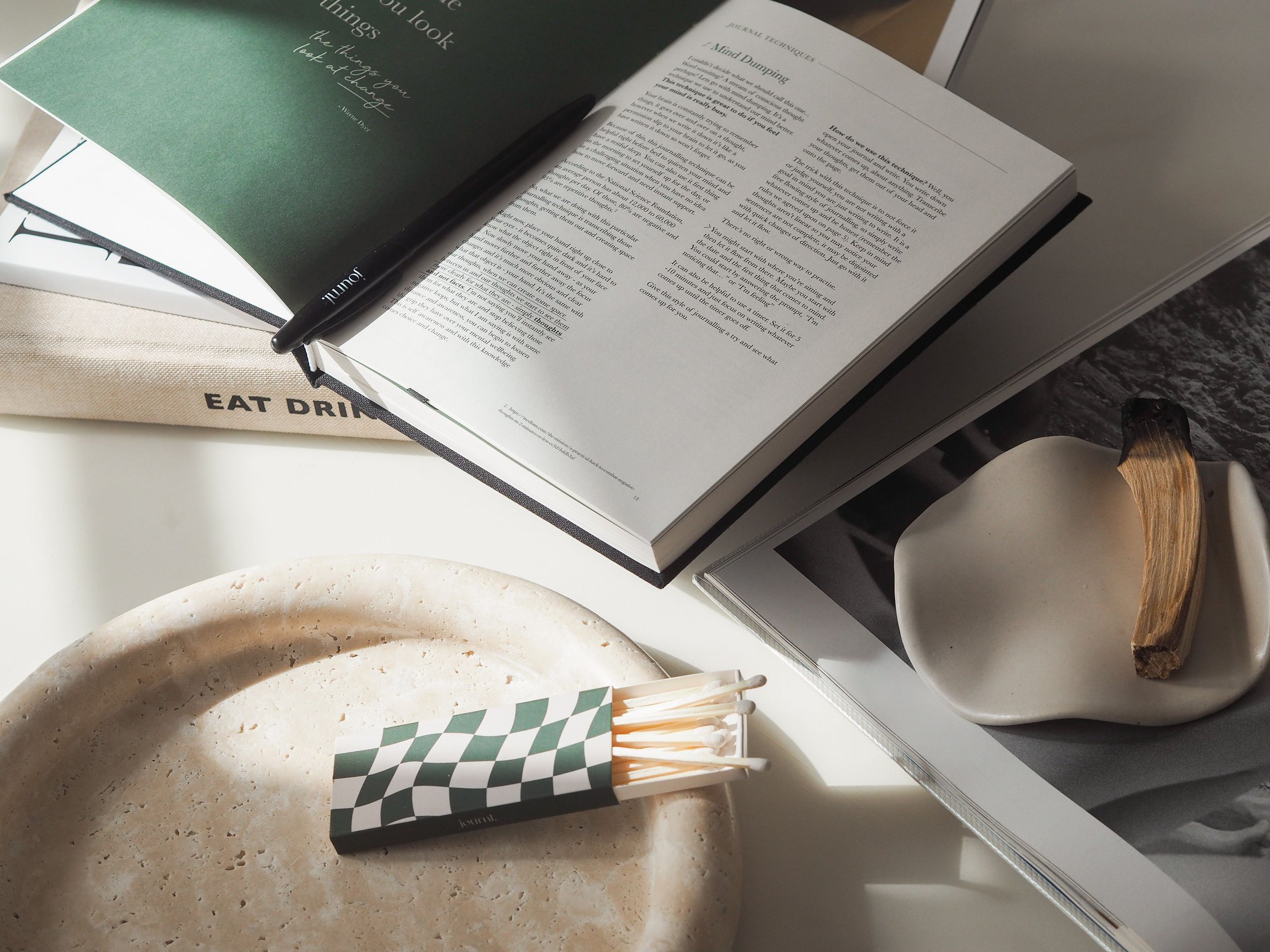 Open book with pages of text, black pen resting on it, a cloth with 