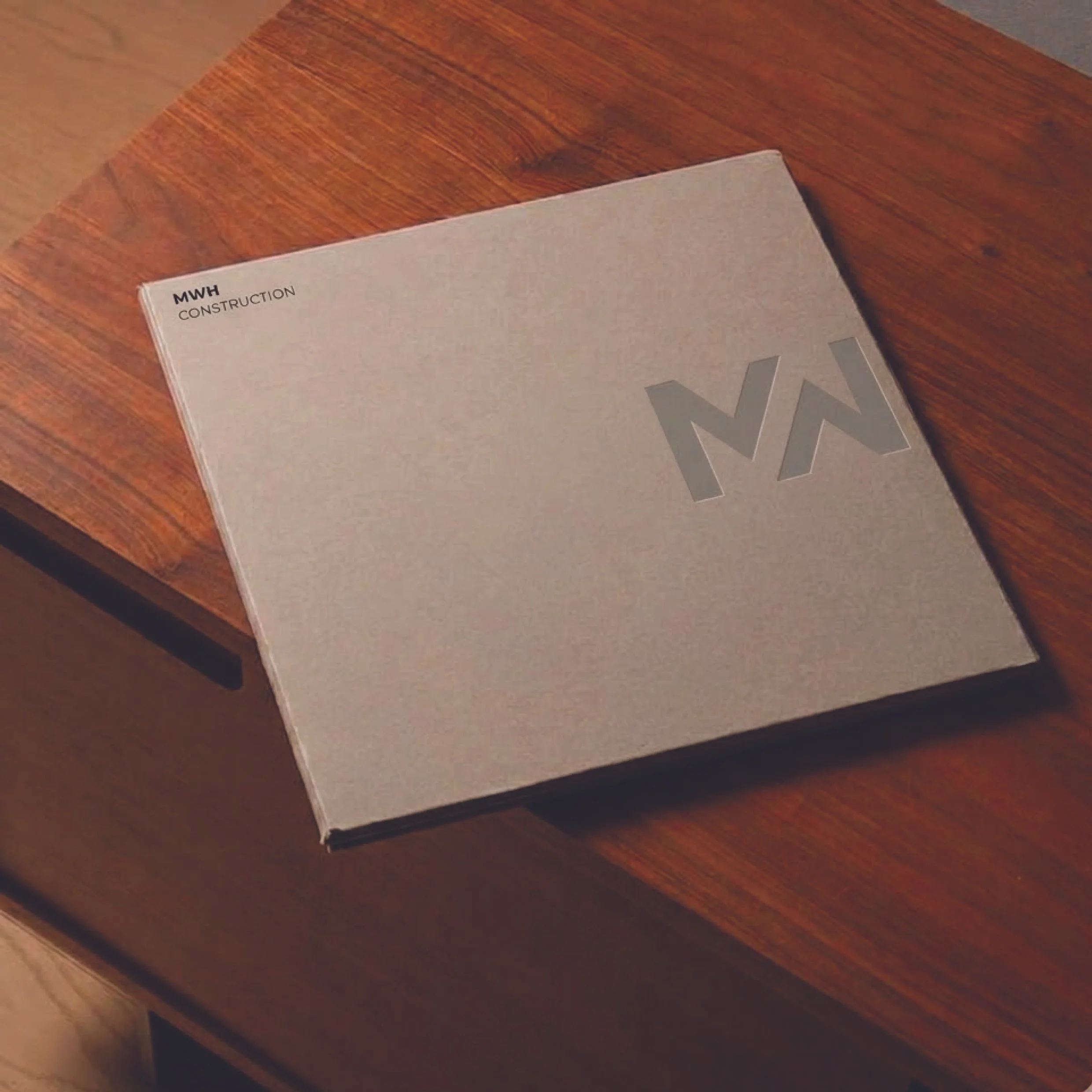 Close-up of a manual titled 'MWH Construction' on a wooden table.