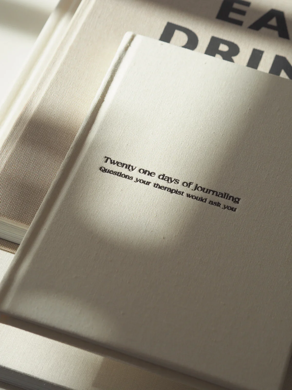 Open journal with the phrase 'Twenty one days of journaling questions your therapist would ask you' printed on the page.