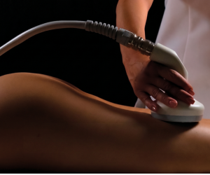 A person receiving a medical or cosmetic ultrasound treatment on their back, with a technician holding the ultrasound device.