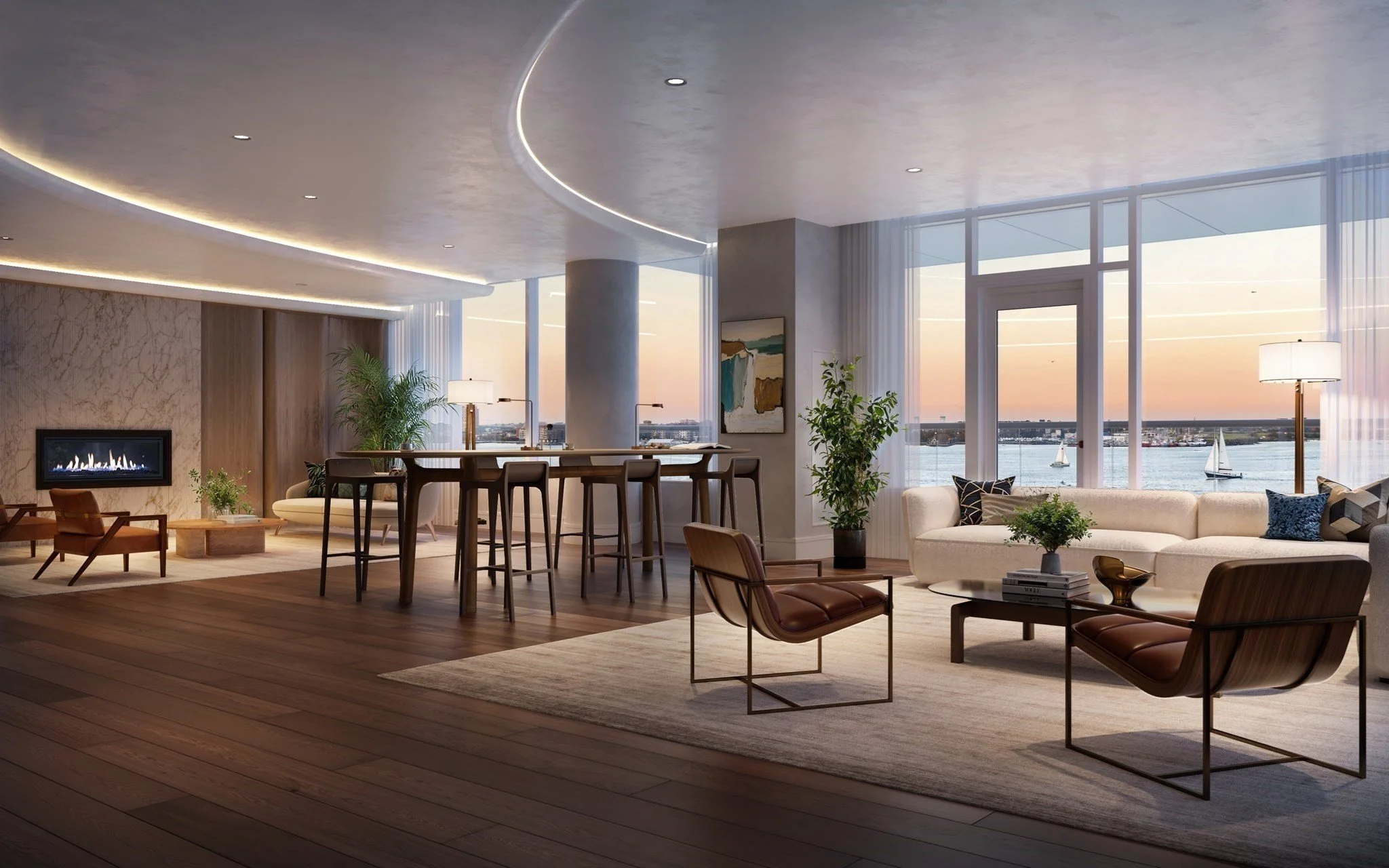 Luxury waterfront living room with fireplace, modern furnishings, floor-to-ceiling windows, and sailboats on the water at sunset