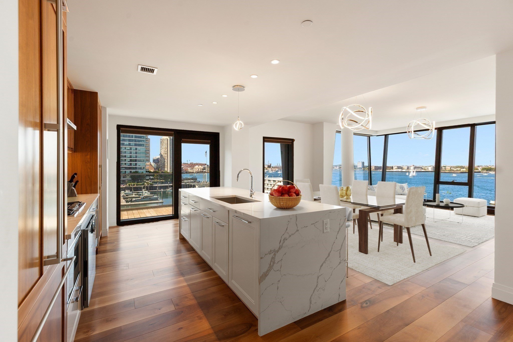 Modern waterfront condo kitchen and dining area with marble island, floor-to-ceiling windows, and harbor views