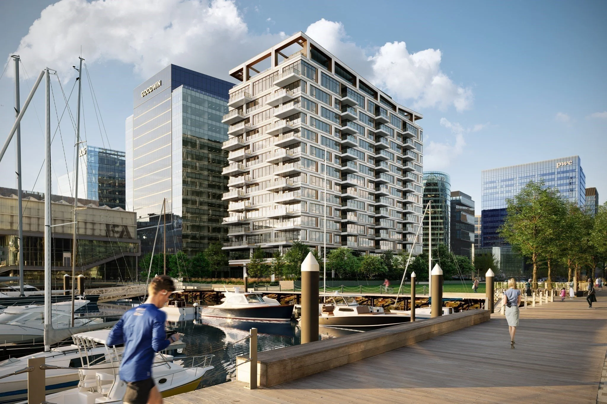 Waterfront marina with boats, modern apartment buildings, office towers, and people walking along a wooden boardwalk.