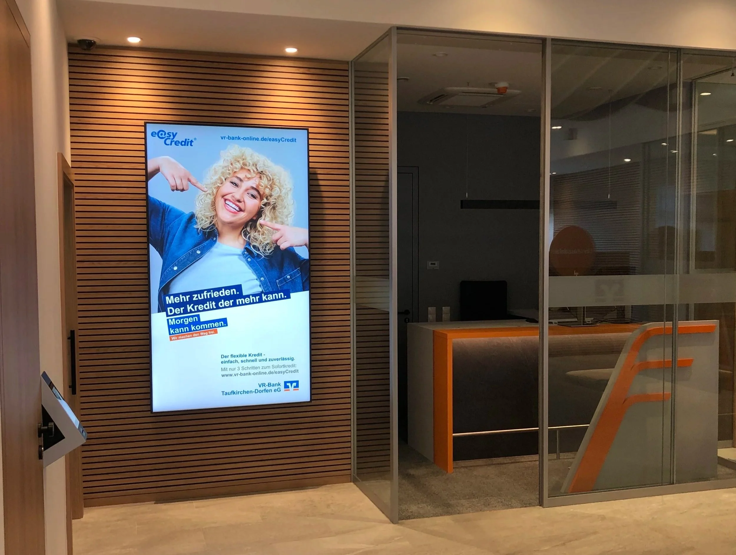 Digitales Werbeplakat für eine Online-Kreditbank mit einem lachenden Mädchen, das in die Kamera zeigt, am rechten Rand eine Glaswand.