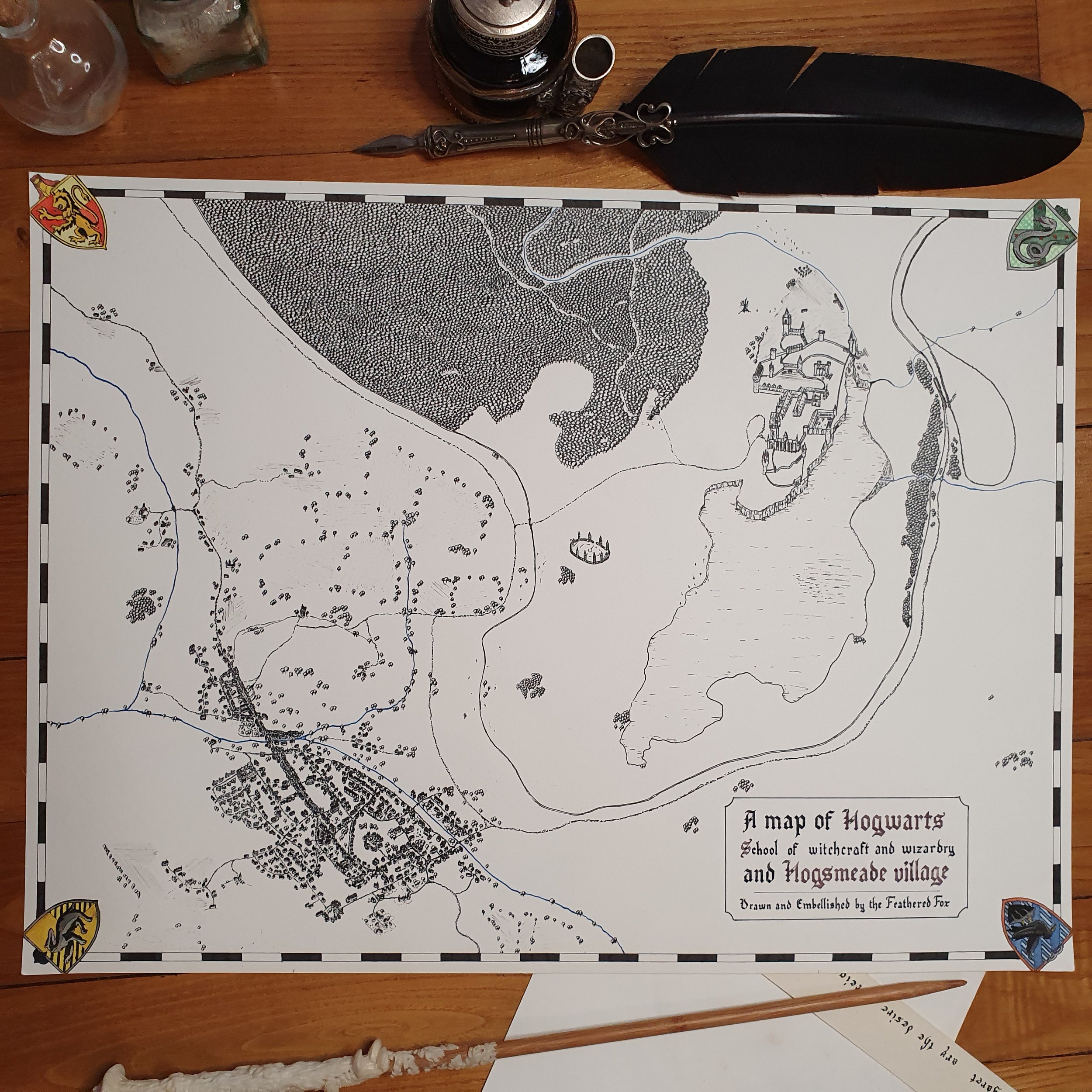 Une carte de Poudlard, l'école de sorcellerie, et du village de Pré-au-lard réalisée à l'encre de Chine et à la plume, avec des éléments décoratifs autour, réalisée pour des fans d'Harry Potter.