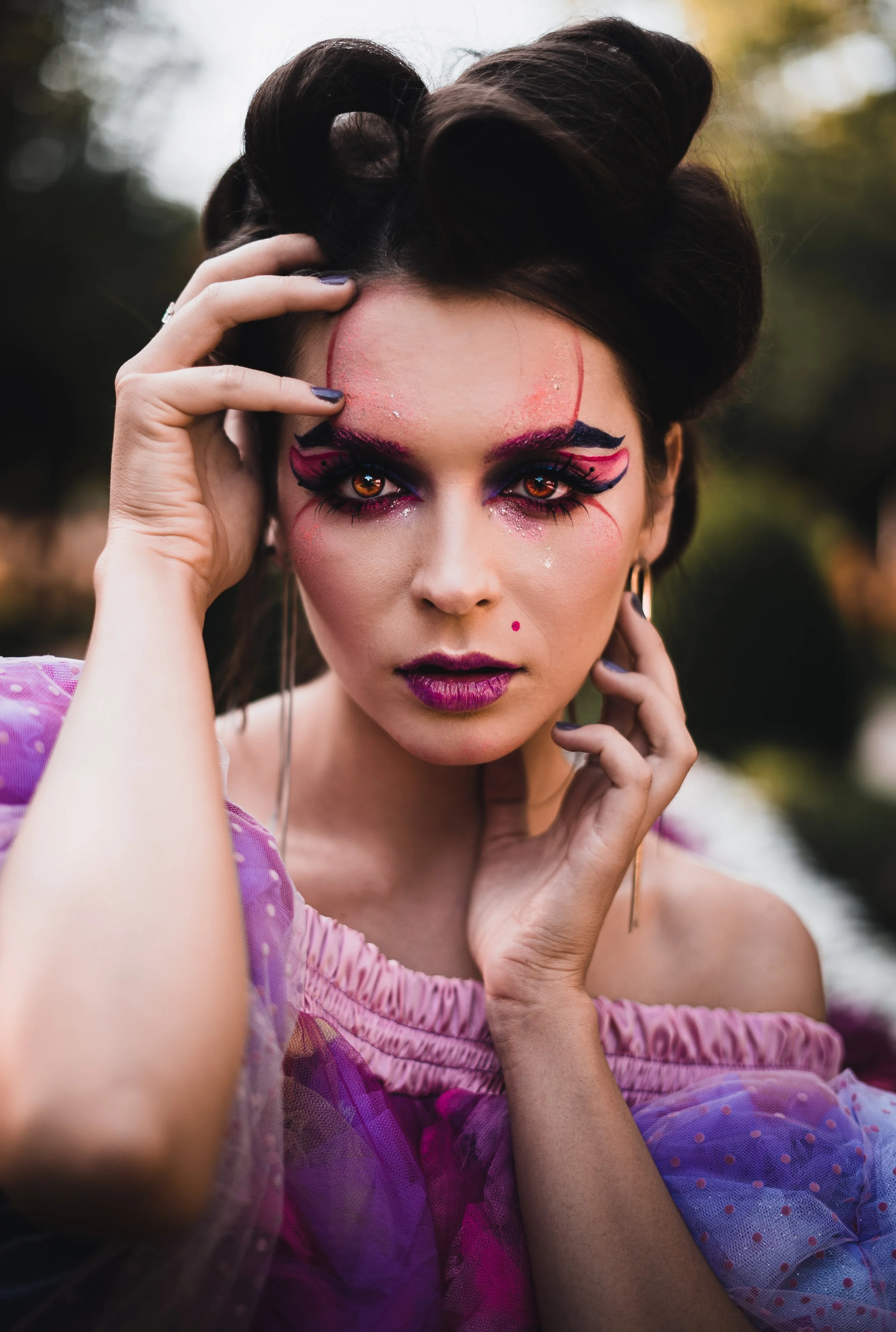 Porträt einer Frau mit buntem Make-up und korsettartigem Kleid, die in der Natur posiert.