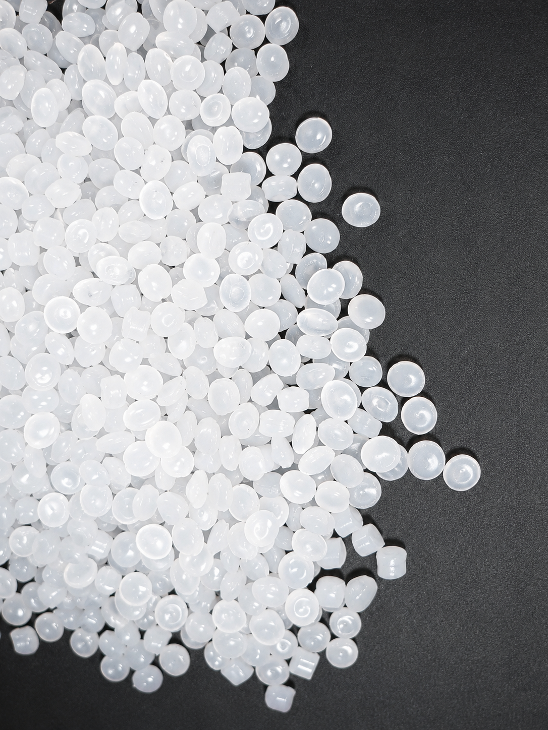 plastic granules / raw material scattered on a black surface.