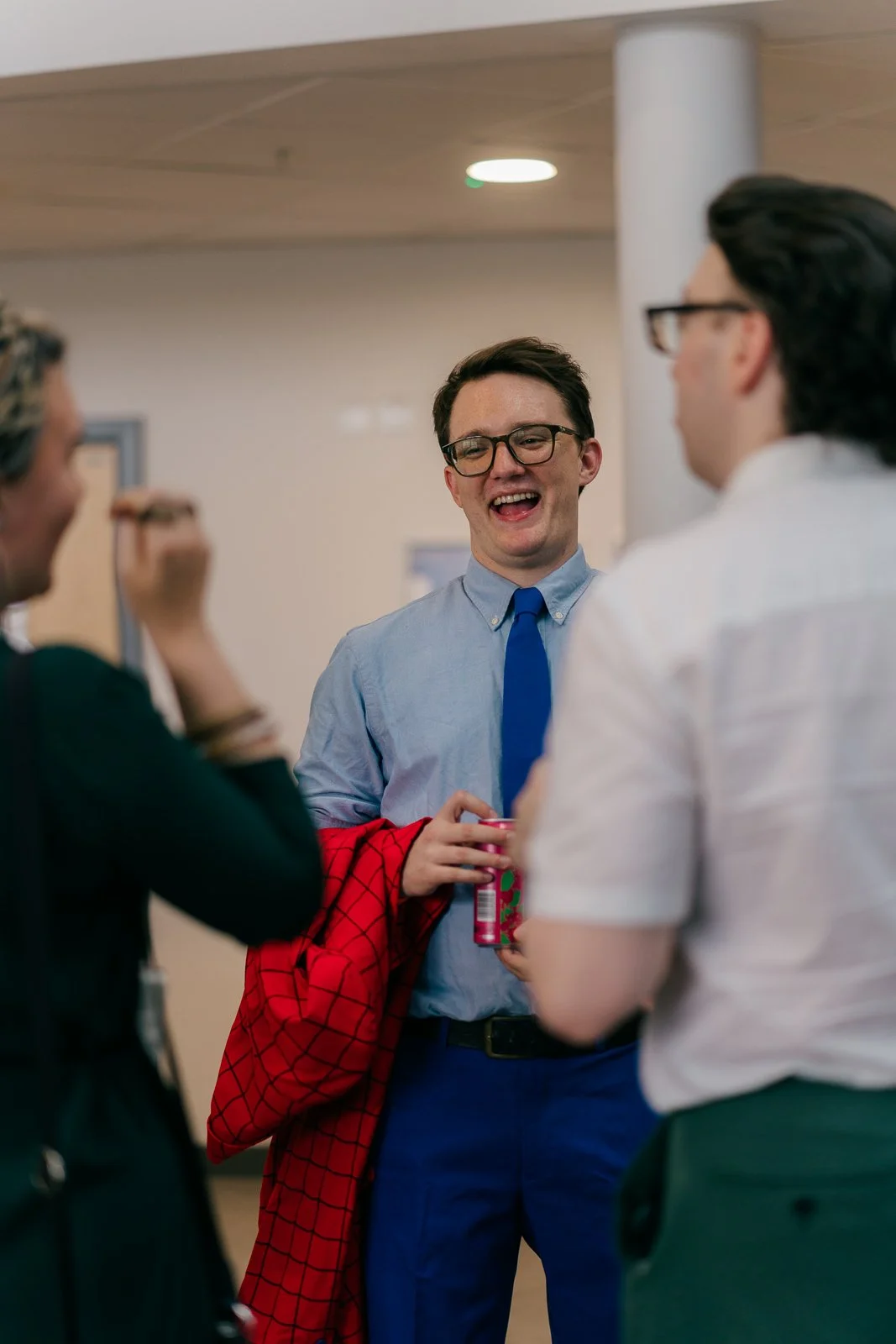 Group of three young adults having a conversation indoors, smiling, and enjoying each other's company.