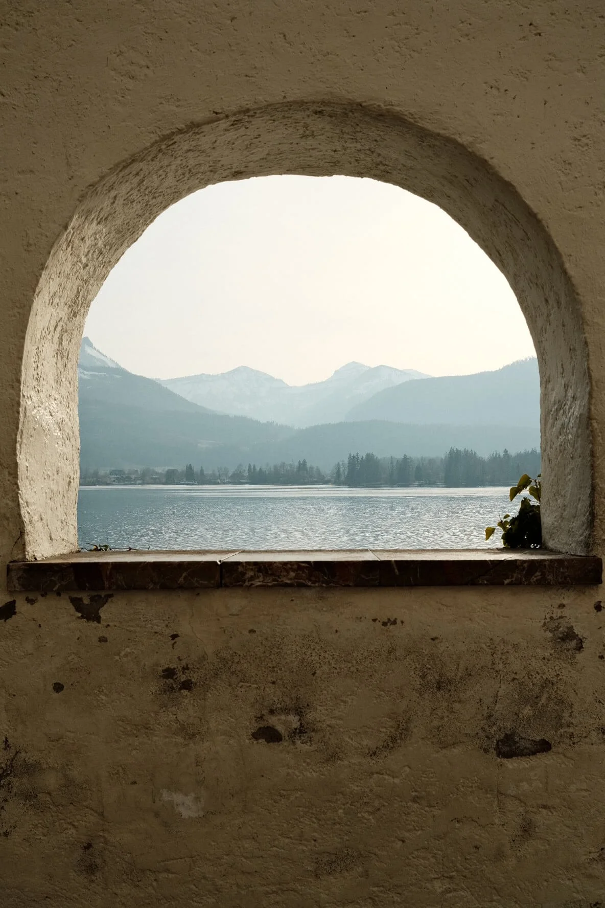 View of a Wolfgangsee and mountains through a stone arched window.