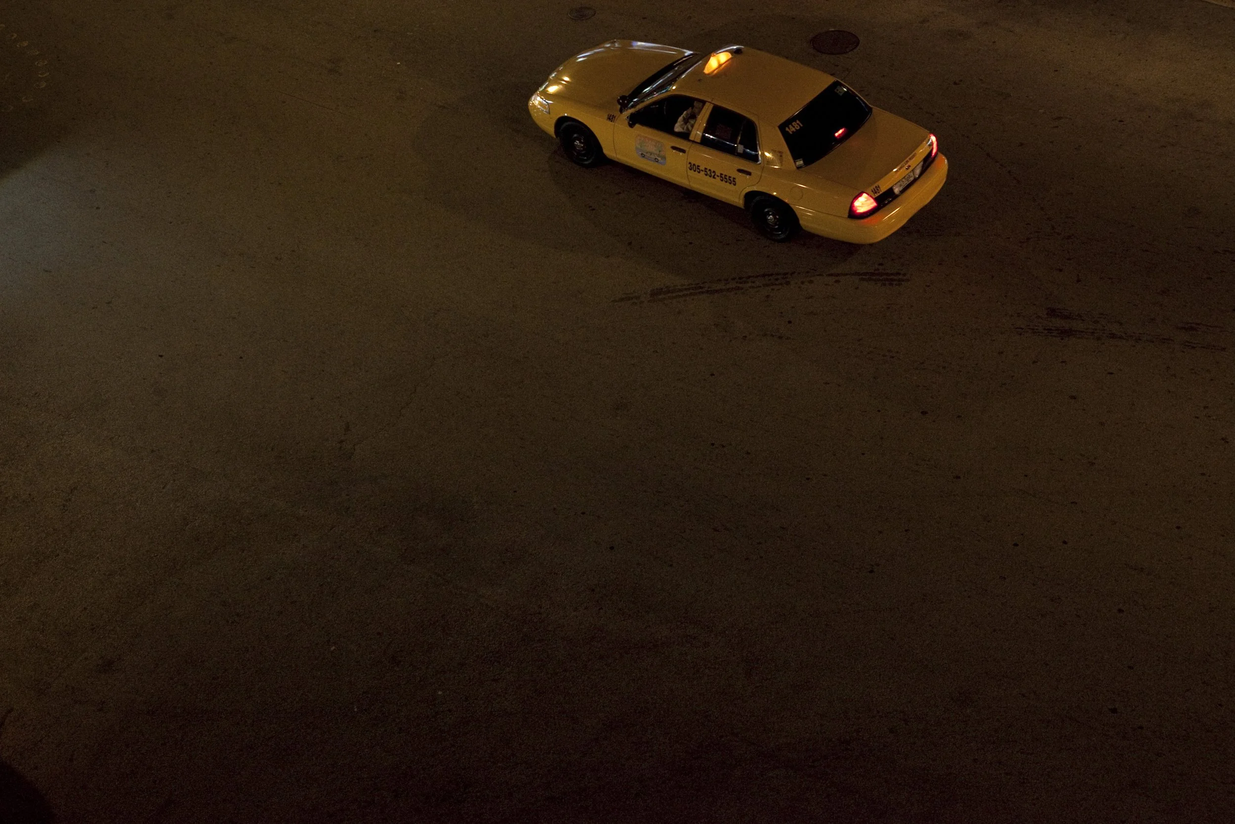 Une voiture de taxi jaune vue de dessus dans une rue sombre.
