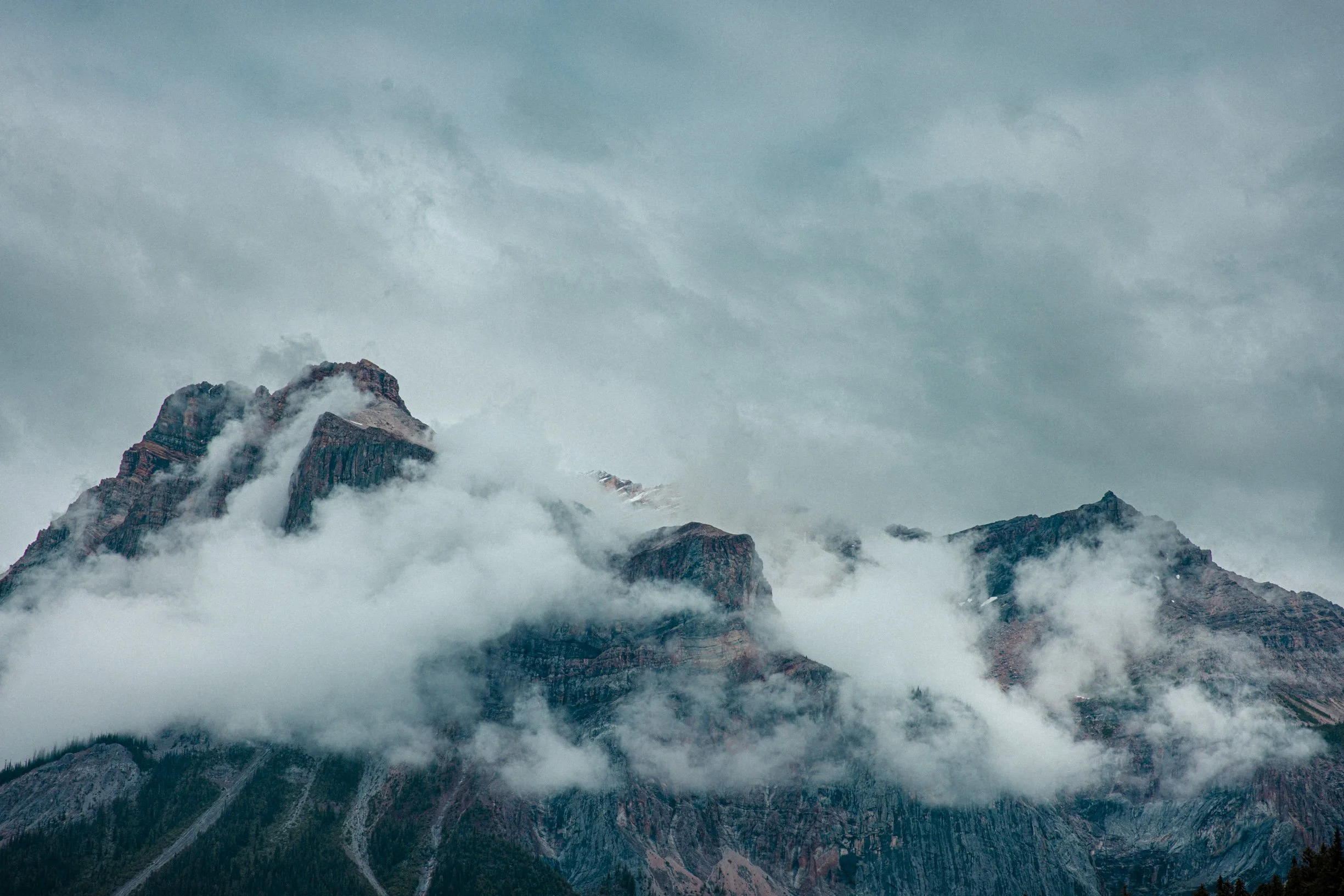 Montagne enneigée entourée de nuages et de brouillard.