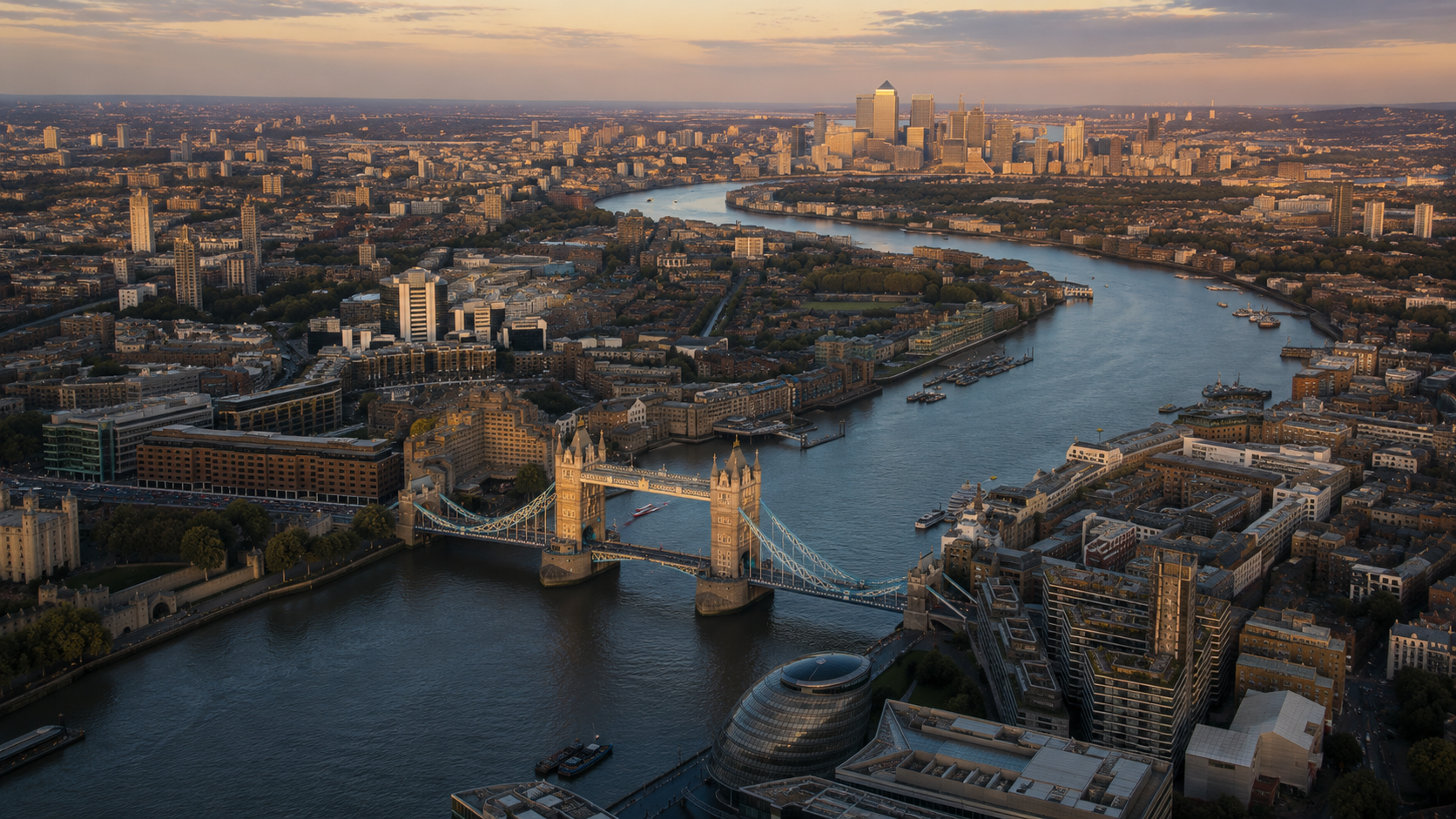 Vista panorámica de Londres al atardecer, mostrando el Puente de Londres sobre el río Támesis, edificios modernos y la silueta del distrito financiero en el fondo.