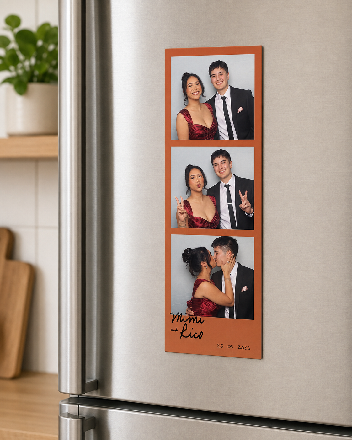 A photo strip on a refrigerator showing three pictures of a couple in formal attire at a special event. The couple is wearing matching deep red and black outfits. The bottom of the strip has handwritten names and a date, indicating a wedding or significant occasion.