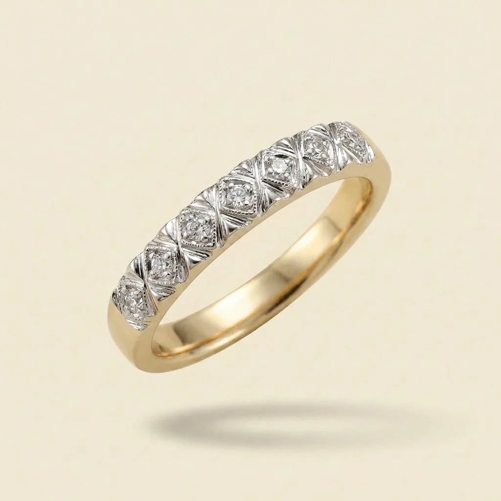 A gold ring with diamond accents and intricate metalwork on a light background.