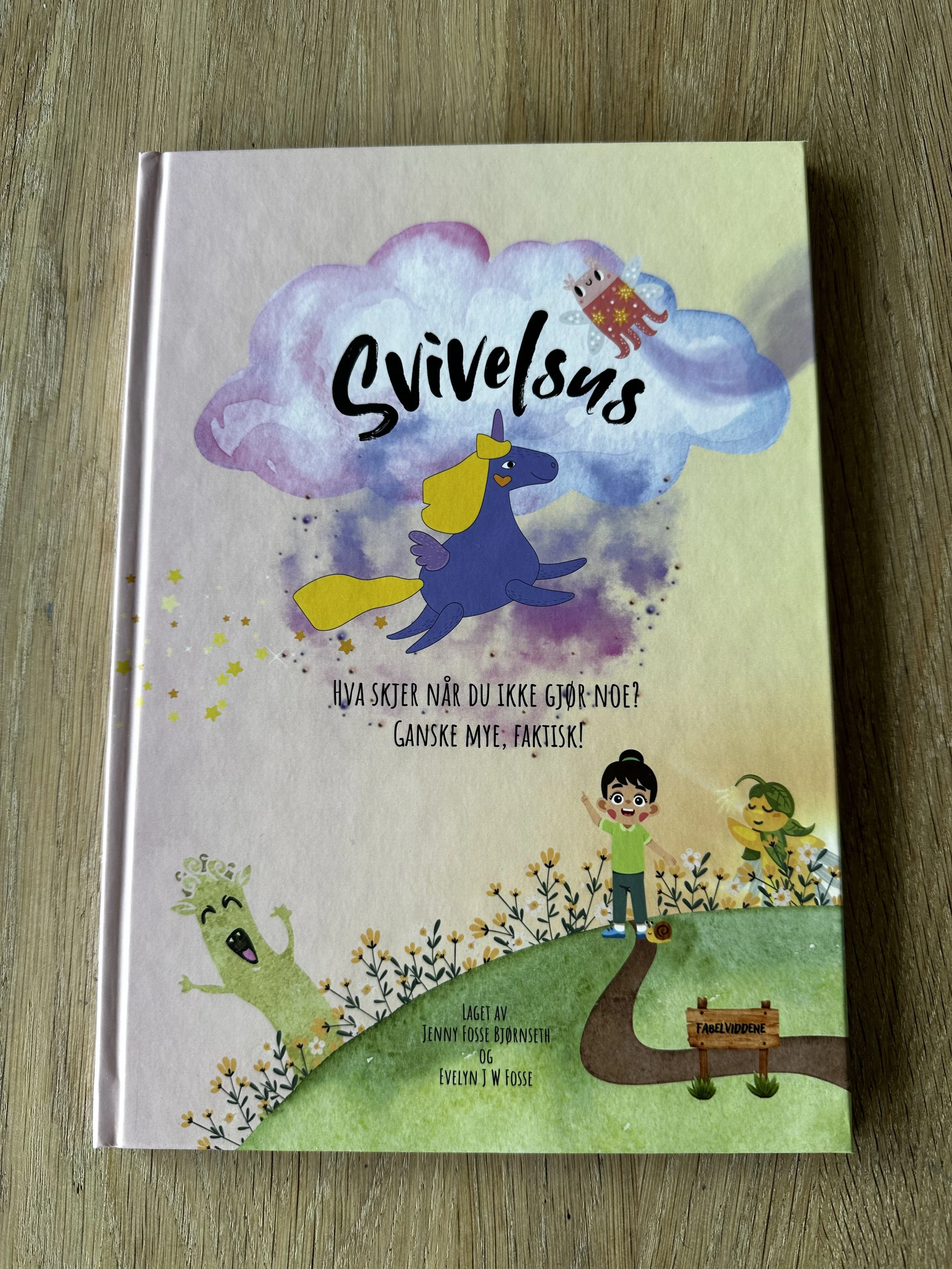Forside av en barnebok med tittelen «Svivelsus». Illustration av en blå enhjørning med gul hale og horn, en flygende liten fe, og en barnefigur som peker oppover. Bakgrunn med skyer, blomster og grønne omgivelser.