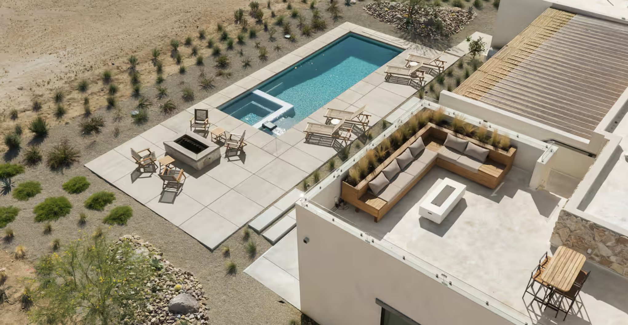 Aerial view of a modern house backyard with a swimming pool, outdoor lounge area, and desert landscaping.