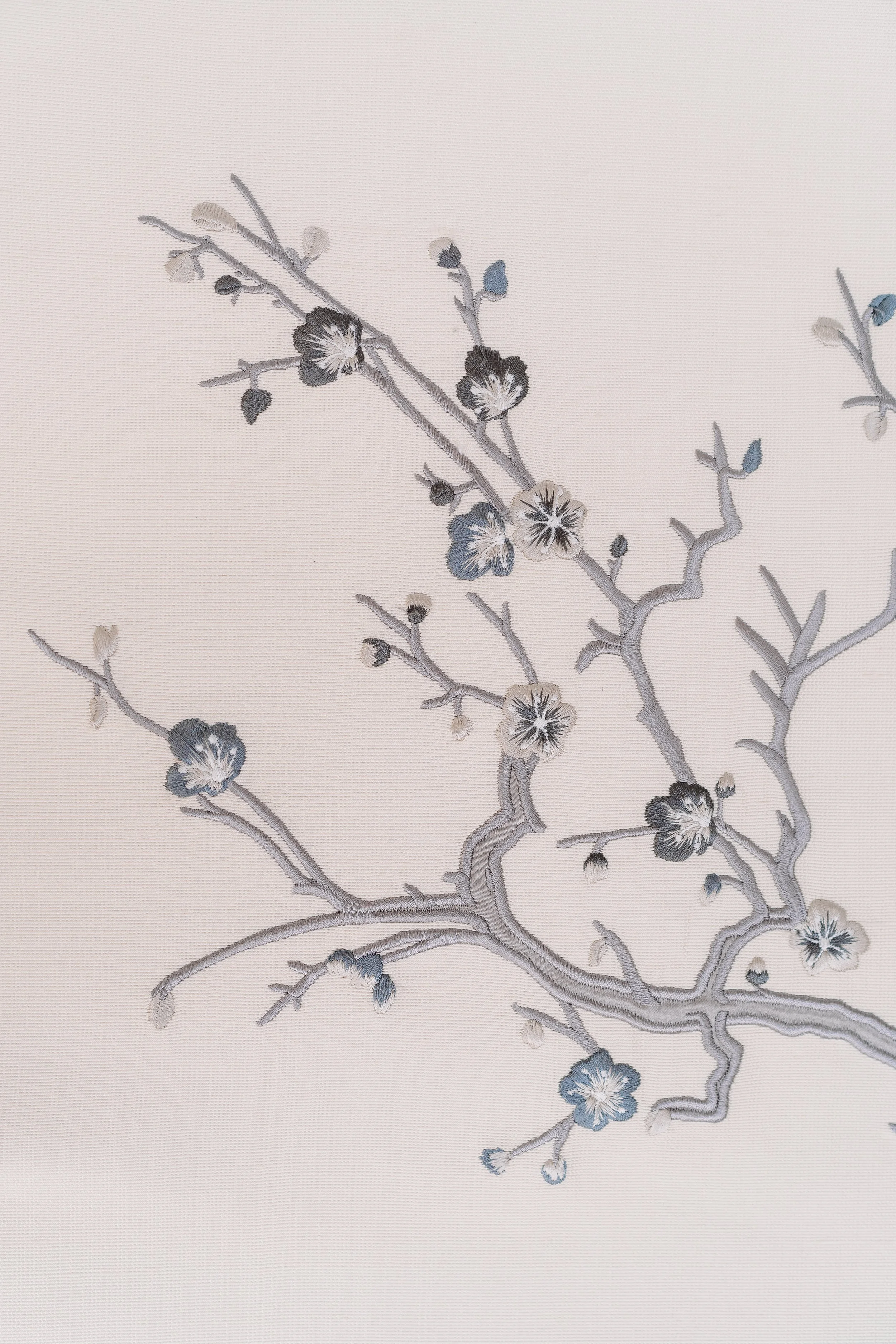 Close-up of embroidered chinoiserie in soft grey, lilac, dark grey and taupe coloured threads