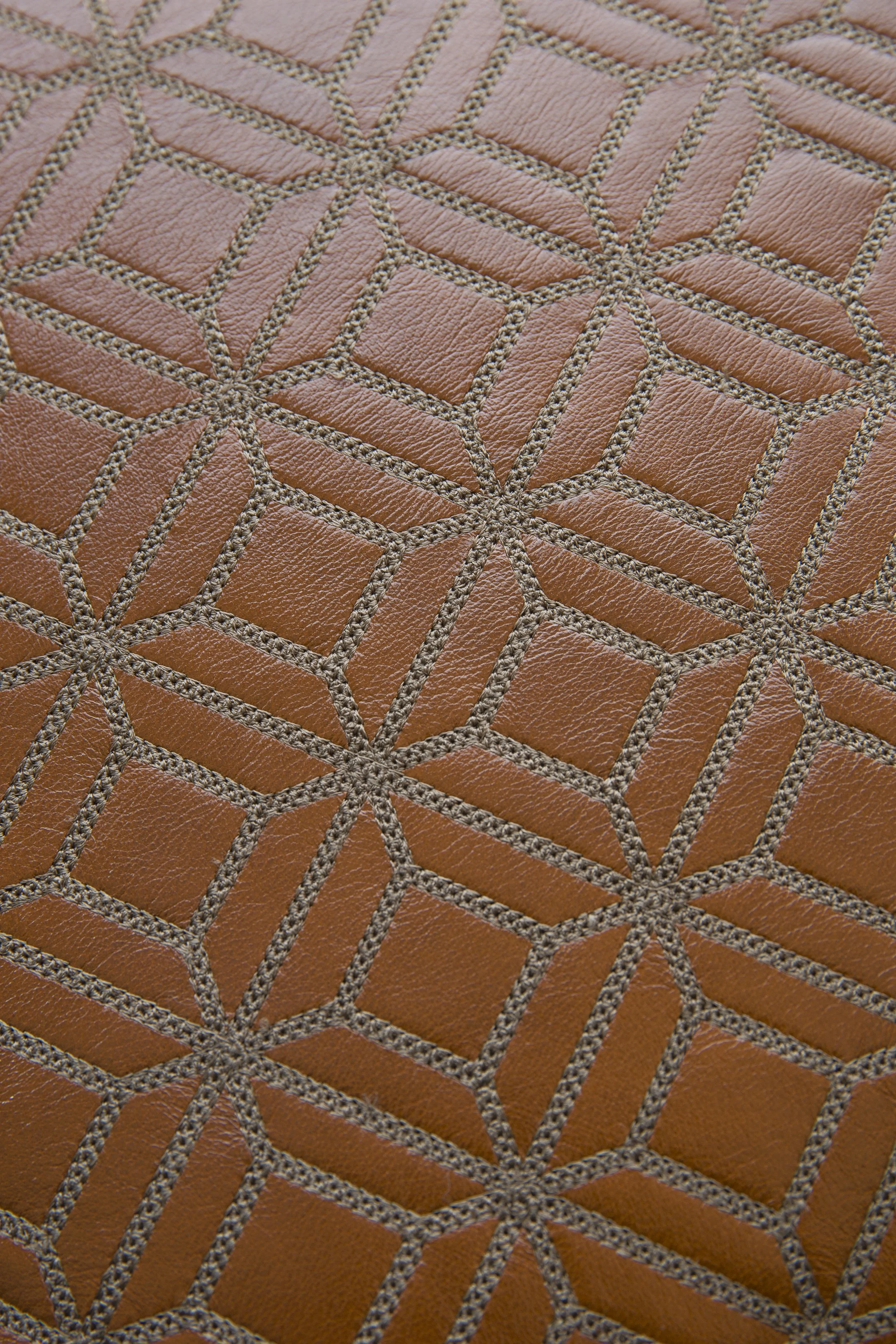 Close-up of a textured leather surface with stitched geometric patterns.