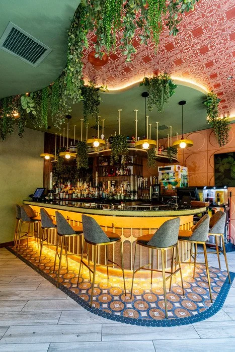 Gustavo's Mexican Grill - Louisville KY- Custom bar featuring a curved wood surround and integrated shelving, highlighted by warm lighting, layered architectural detailing, and decorative finishes that frame the bar area and emphasize craftsmanship.