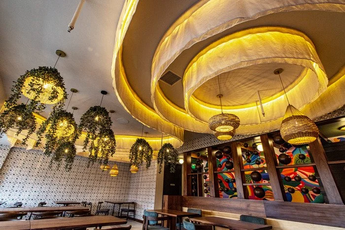 Gustavo's Mexican Grill - Louisville KY Interior of a restaurant highlighting a custom wood lighting installation suspended from the ceiling, paired with a striking wood art installation 
