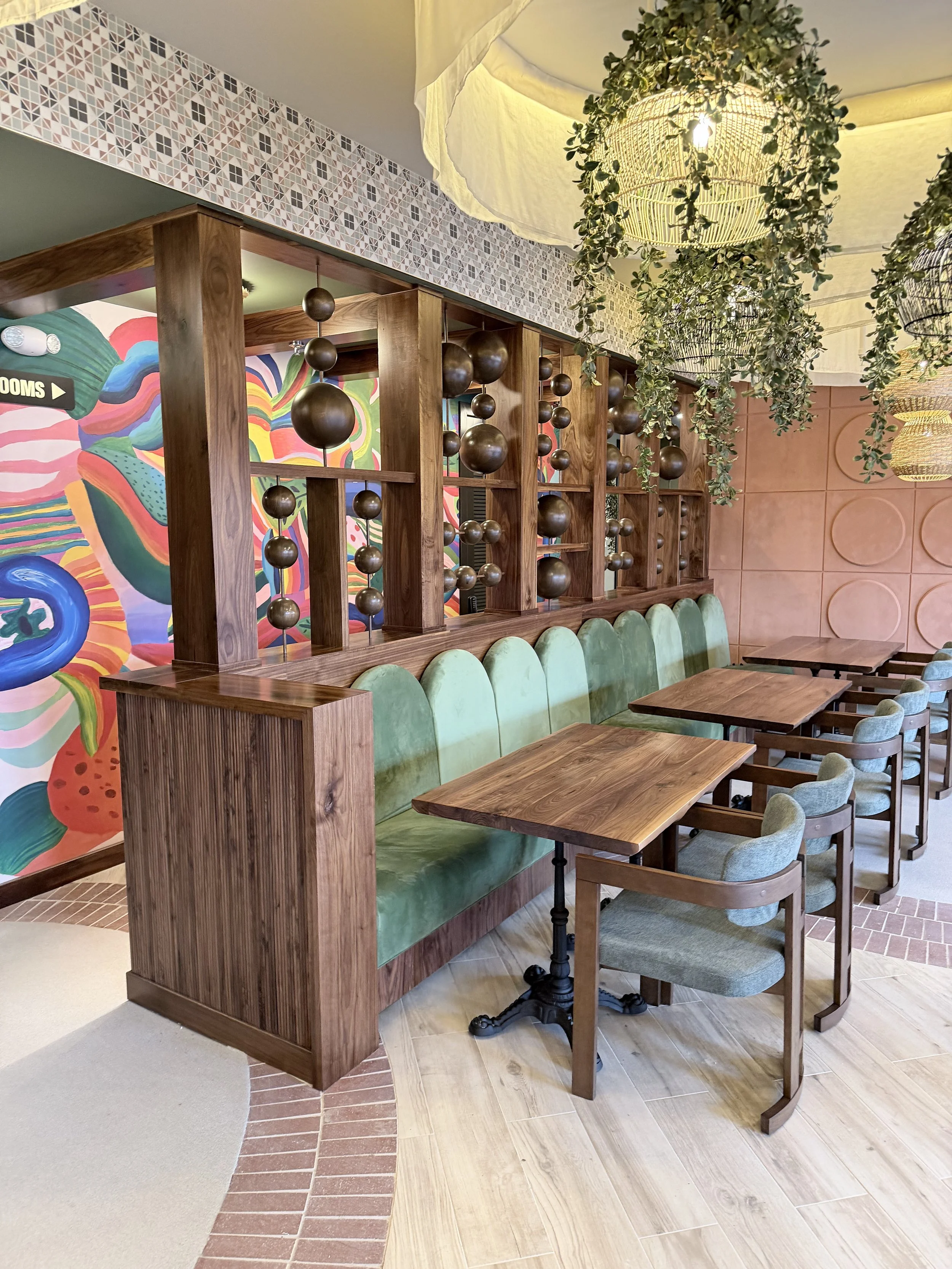 Gustavo's Mexican Grill - KY Cozy dining area showcasing a custom wood art feature integrated into the wall design, emphasizing craftsmanship and natural wood textures, enhanced by warm lighting, hanging decorative elements, and surrounding greenery.
