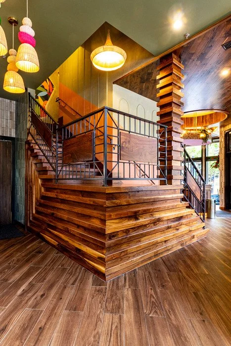 Gustavo's Mexican Grill - Louisville KY Interior of a restaurant showcasing a custom staircase with a striking geometric wood art feature, highlighting precise craftsmanship and layered wood detailing integrated into the stair design.