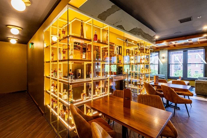 Fully custom tequila tasting room featuring handcrafted wood shelving designed to display liquor bottles and decorative vessels, with integrated architectural detailing that highlights the warmth and craftsmanship of the wood throughout the space.