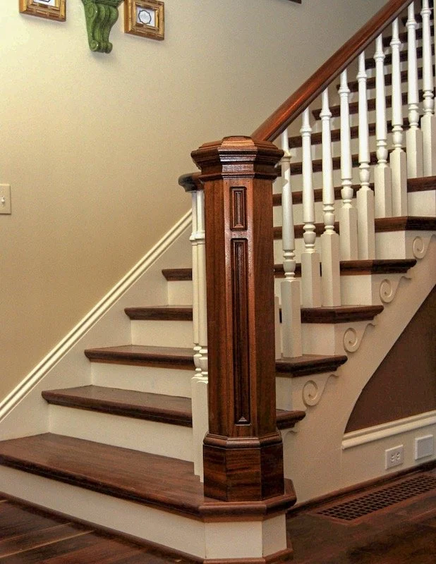 Interior view showcasing a custom-crafted staircase with dark wood treads, detailed white spindles, and a prominent wood newel post, emphasizing the craftsmanship and architectural detailing that define the stairway.
