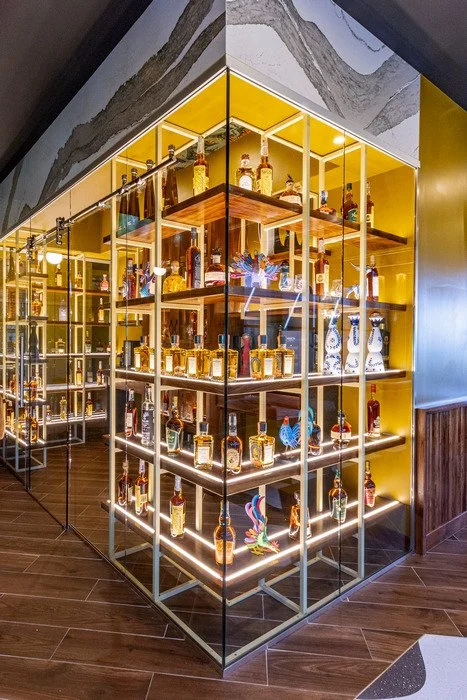 Fully custom tequila tasting room featuring handcrafted wood shelving designed to display liquor bottles and decorative vessels, with integrated architectural detailing that highlights the warmth and craftsmanship of the wood throughout the space.