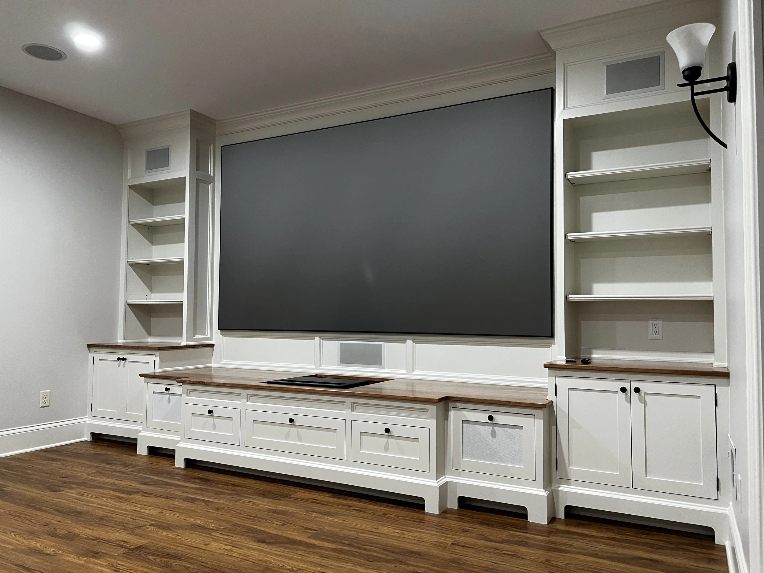 Living room featuring a custom-built wood entertainment center with integrated shelving and a wall-mounted display, designed as a focal architectural element that blends seamlessly with surrounding finishes.