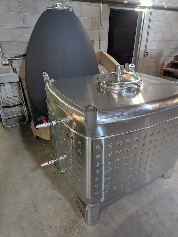 Stainless steel fermentation tank with a rounded lid and several control valves.