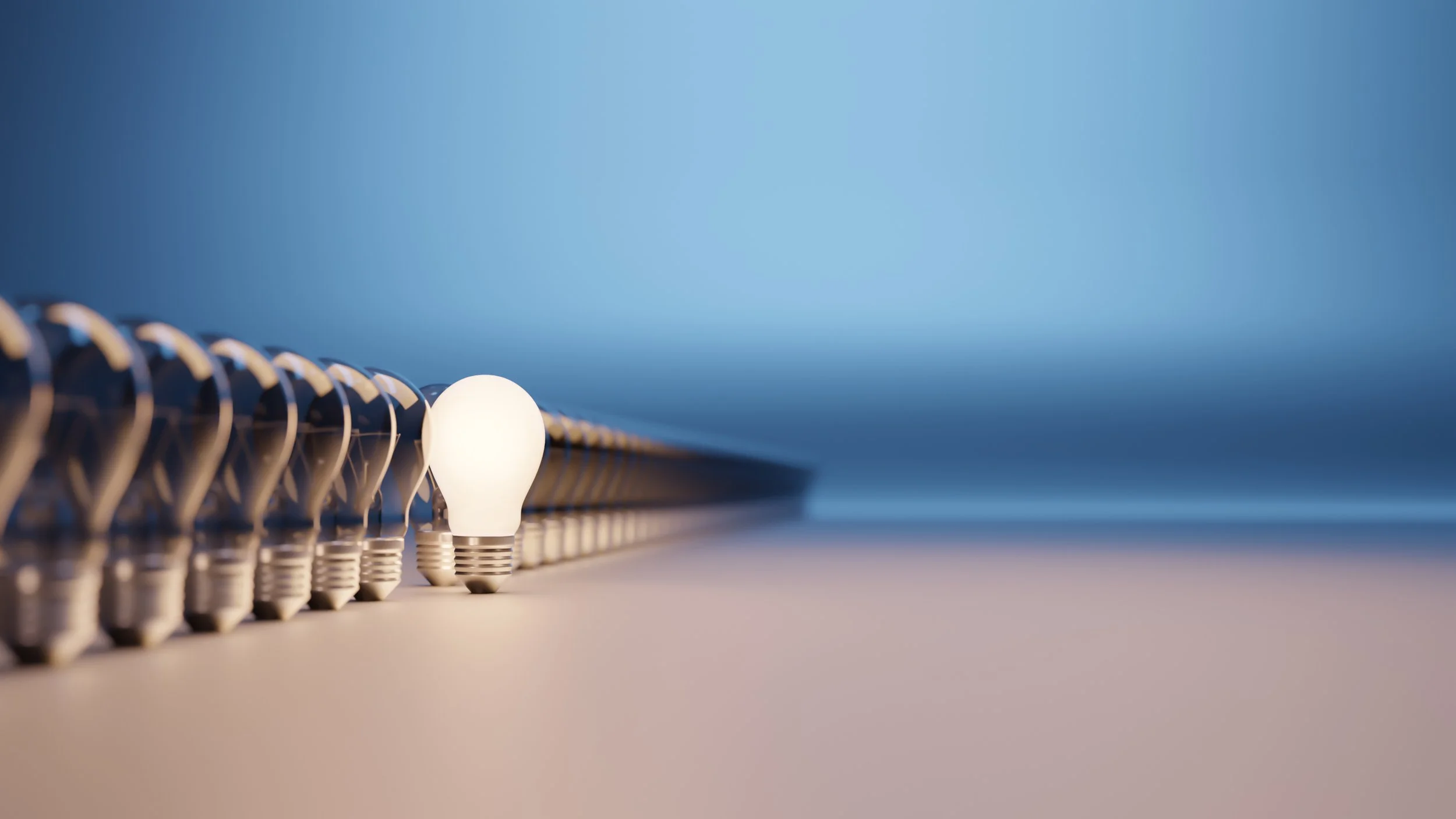 Close-up image of a row of light bulbs on a strip, with a plain gradient blue background.