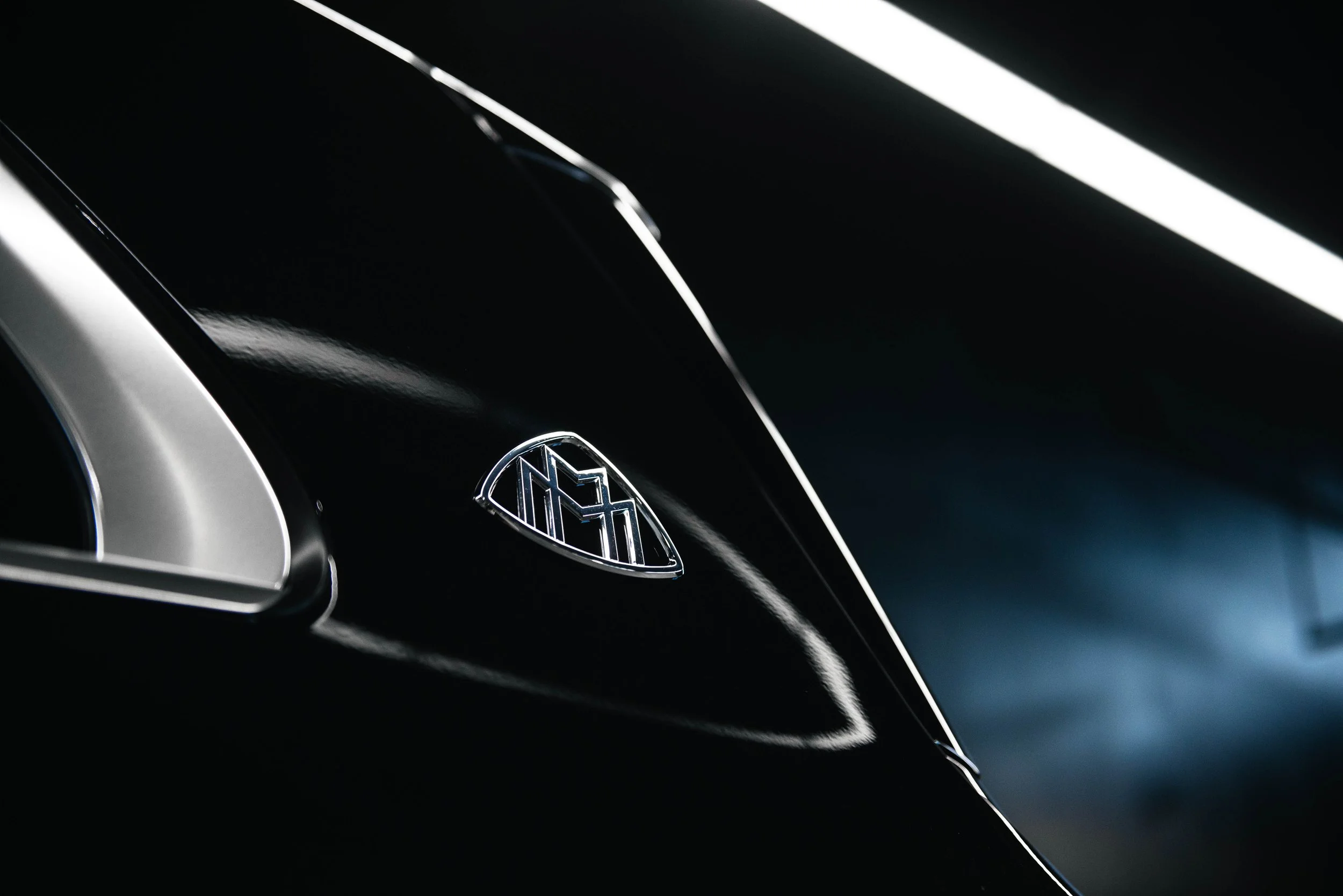 Close-up of a black car with a visible logo on the hood.