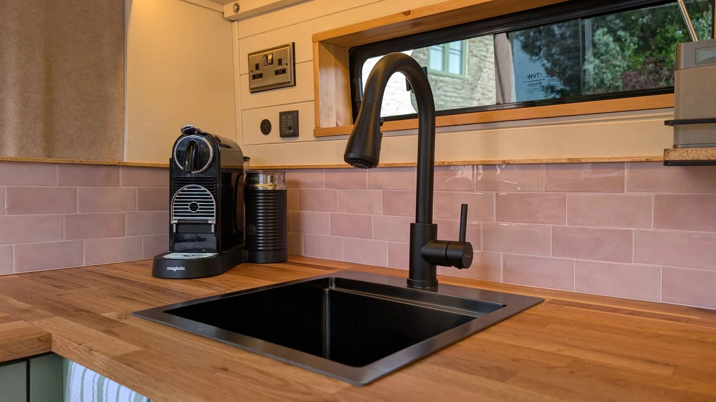 Handcrafted Campervan Kitchen countertop with a black coffee machine, a black water filter, a black sink tap.