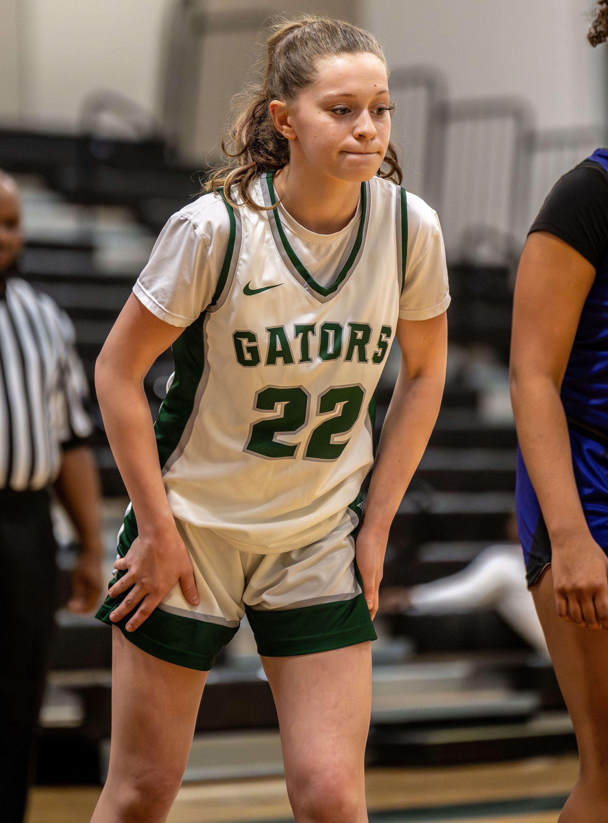 A female basketball player wearing a white Gators jersey with the number 22, standing on a gym court during a game.