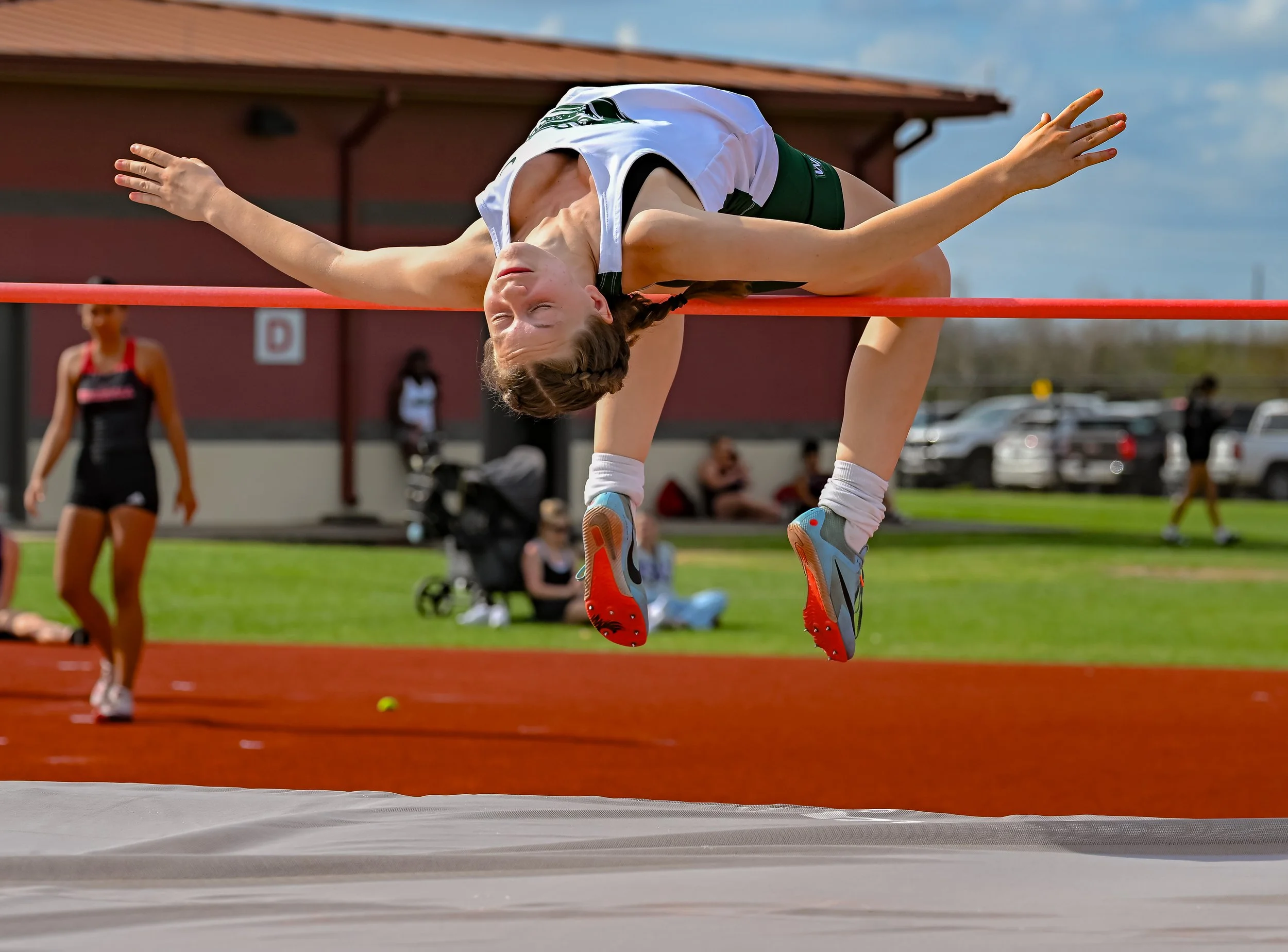 Young female athlete performing a high jump during a track and field event.