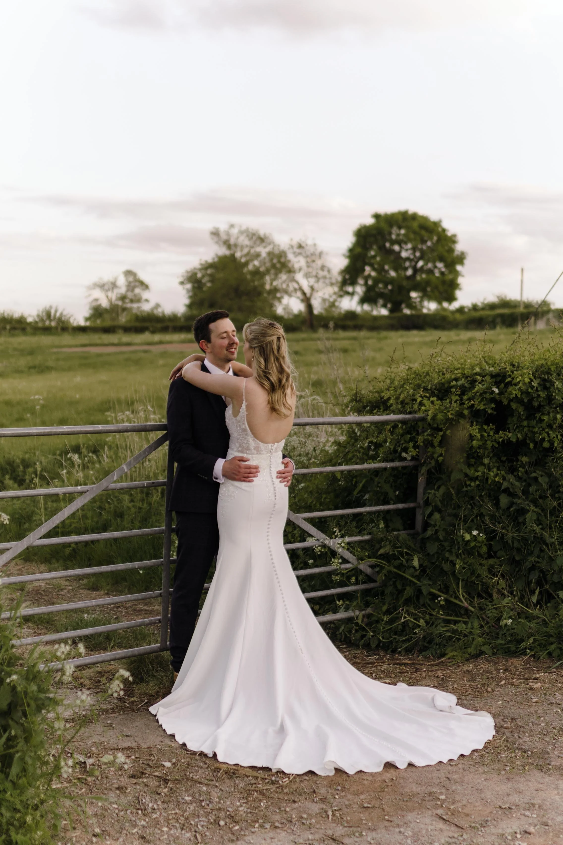 A bride and groom holding and smiling each other with Derbyshire green field in background