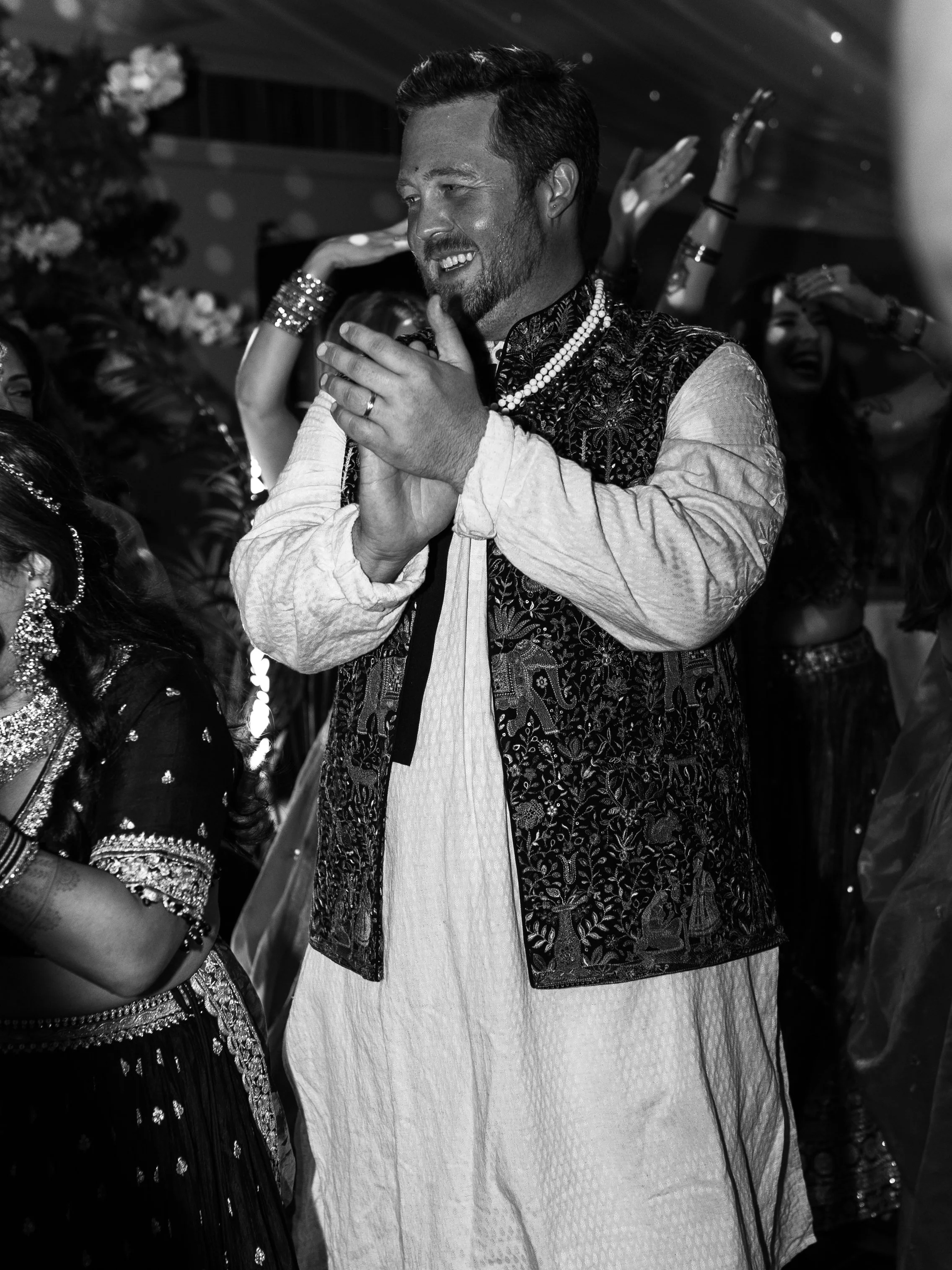 Black and white image of groom smiling and dancing on the dancefloor