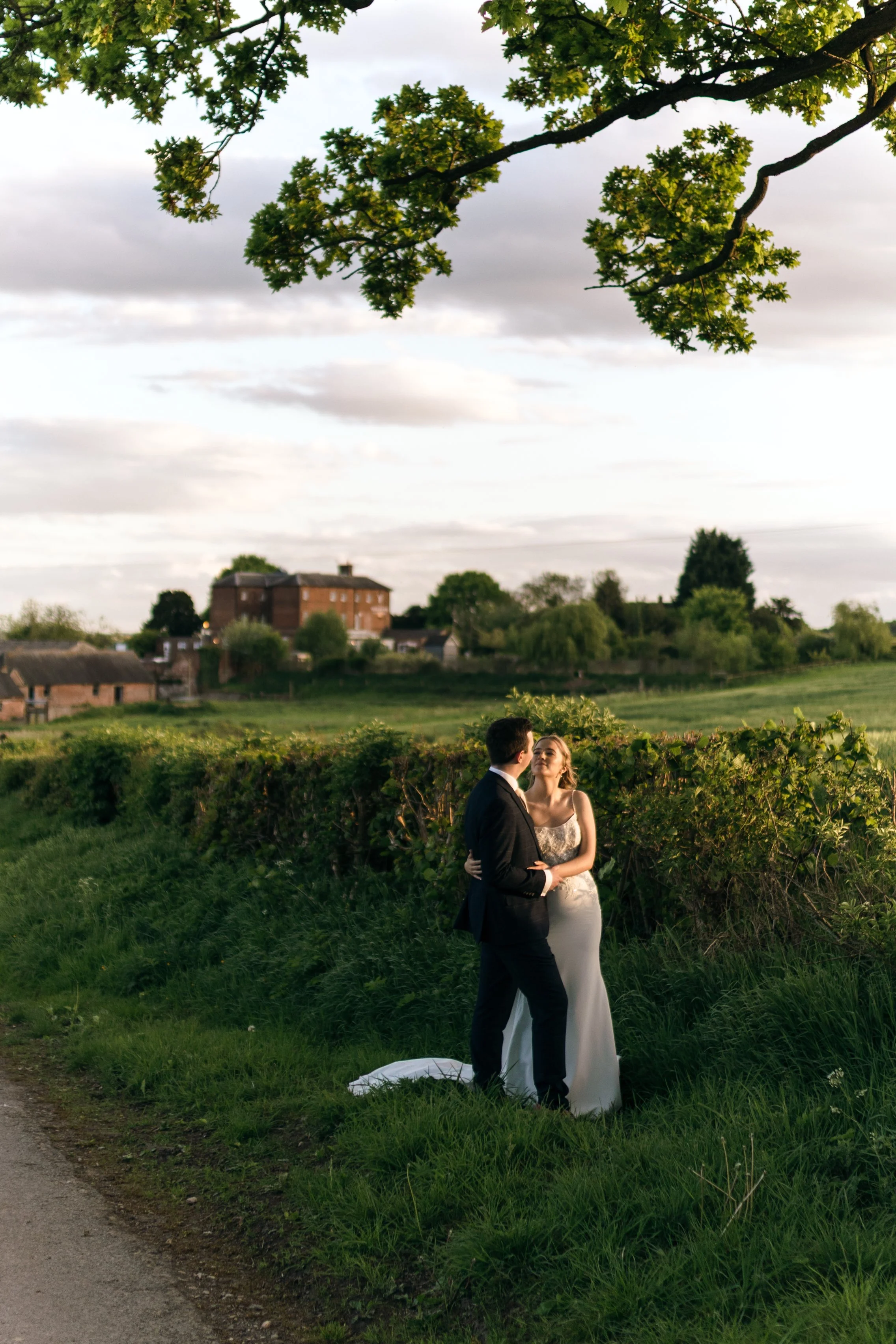 A bride and groom looking at each other during sunset with Kedleston Country House in the background