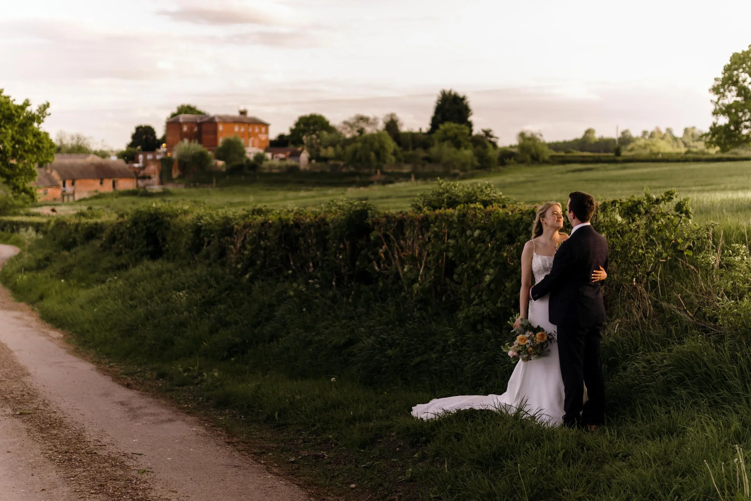 A bride and groom gazing at each other with Kedleston Country House in the background
