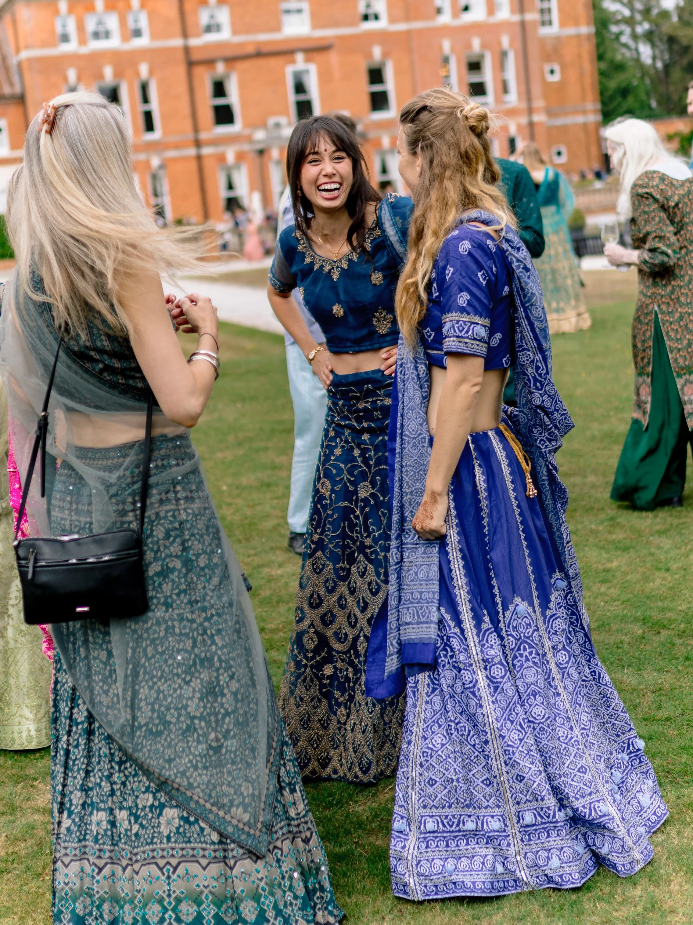 A candid shot of a wedding guest laughing with a country house in the background