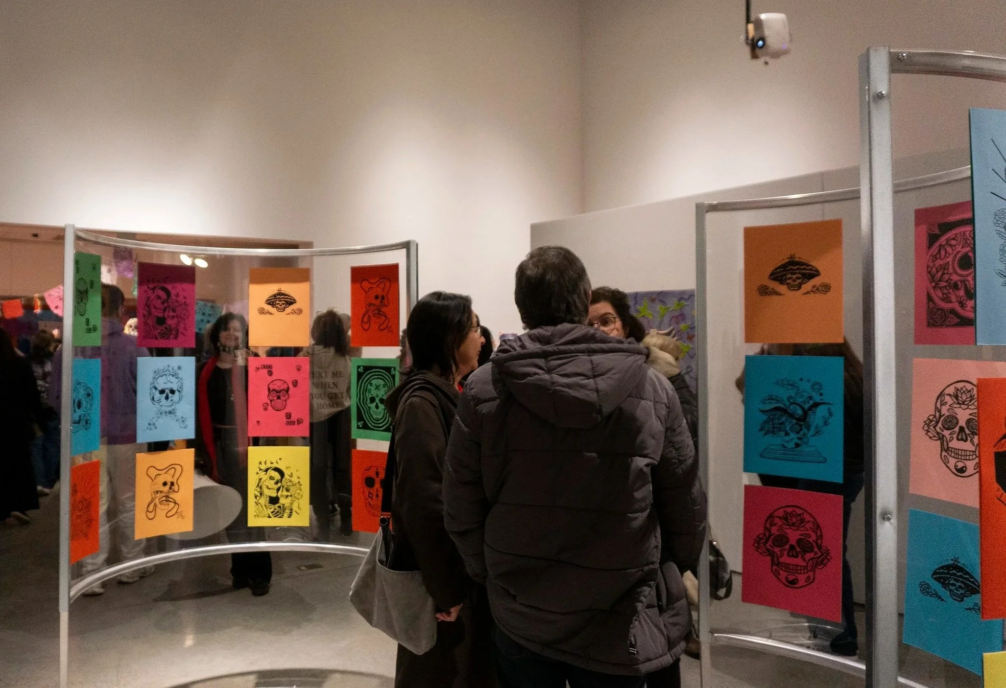 People standing at an art exhibition with colorful artwork of skulls and animals on display.